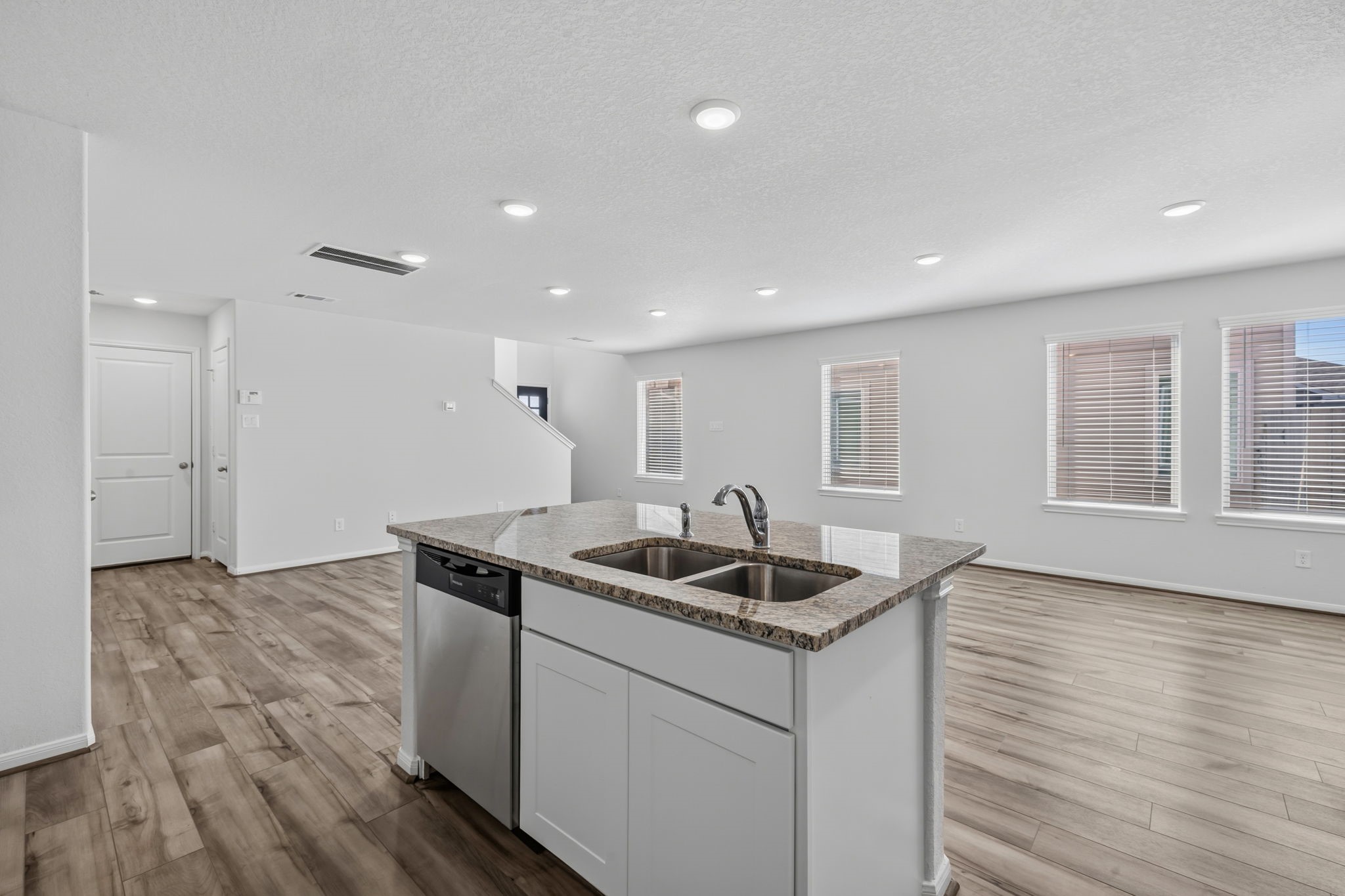 KITCHEN II - The center island has an undermount double sink and dishwasher, and it overlooks the bright living area with its row of windows.