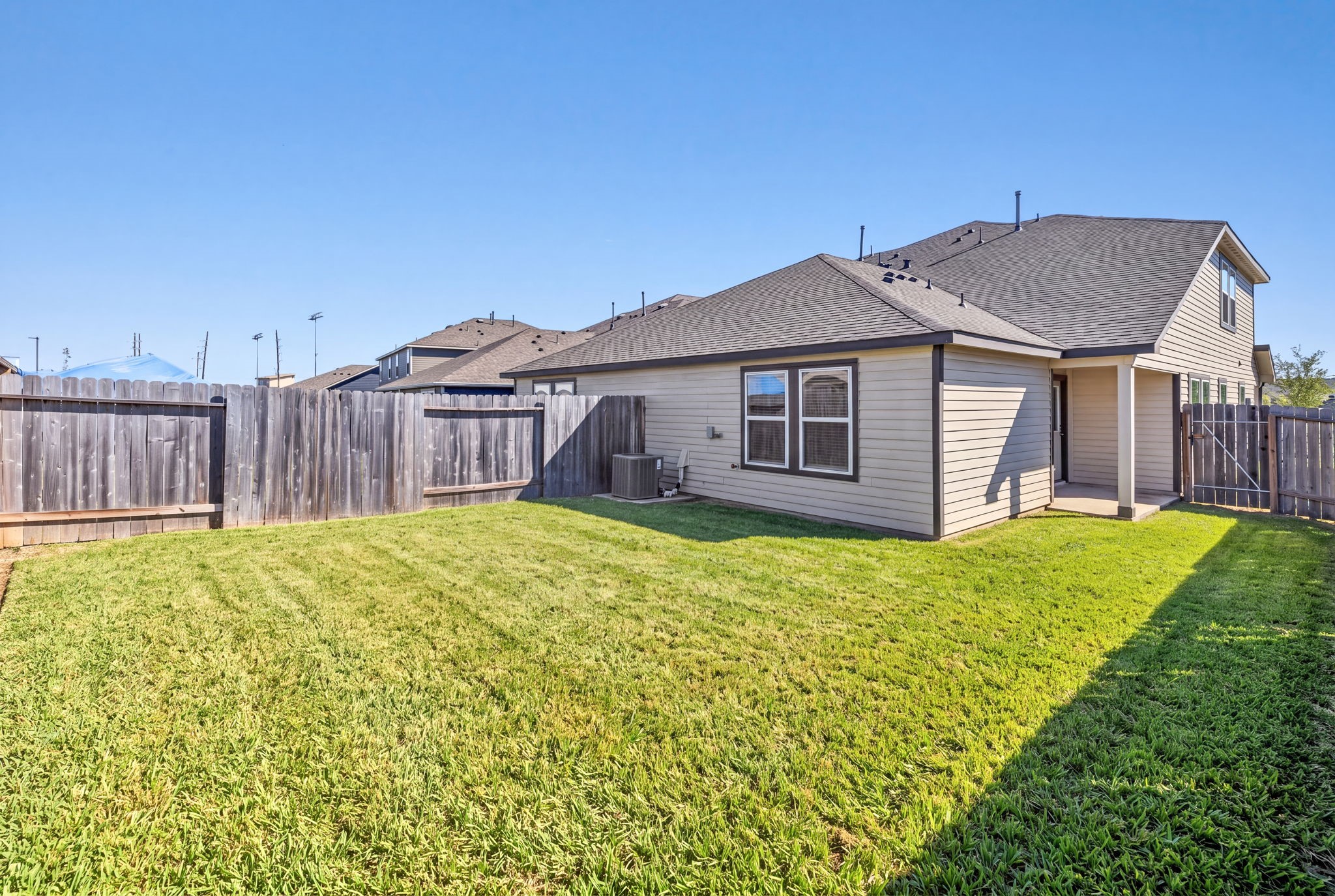 The rear view of the home shows the fenced yard, covered patio, and side gate access.
