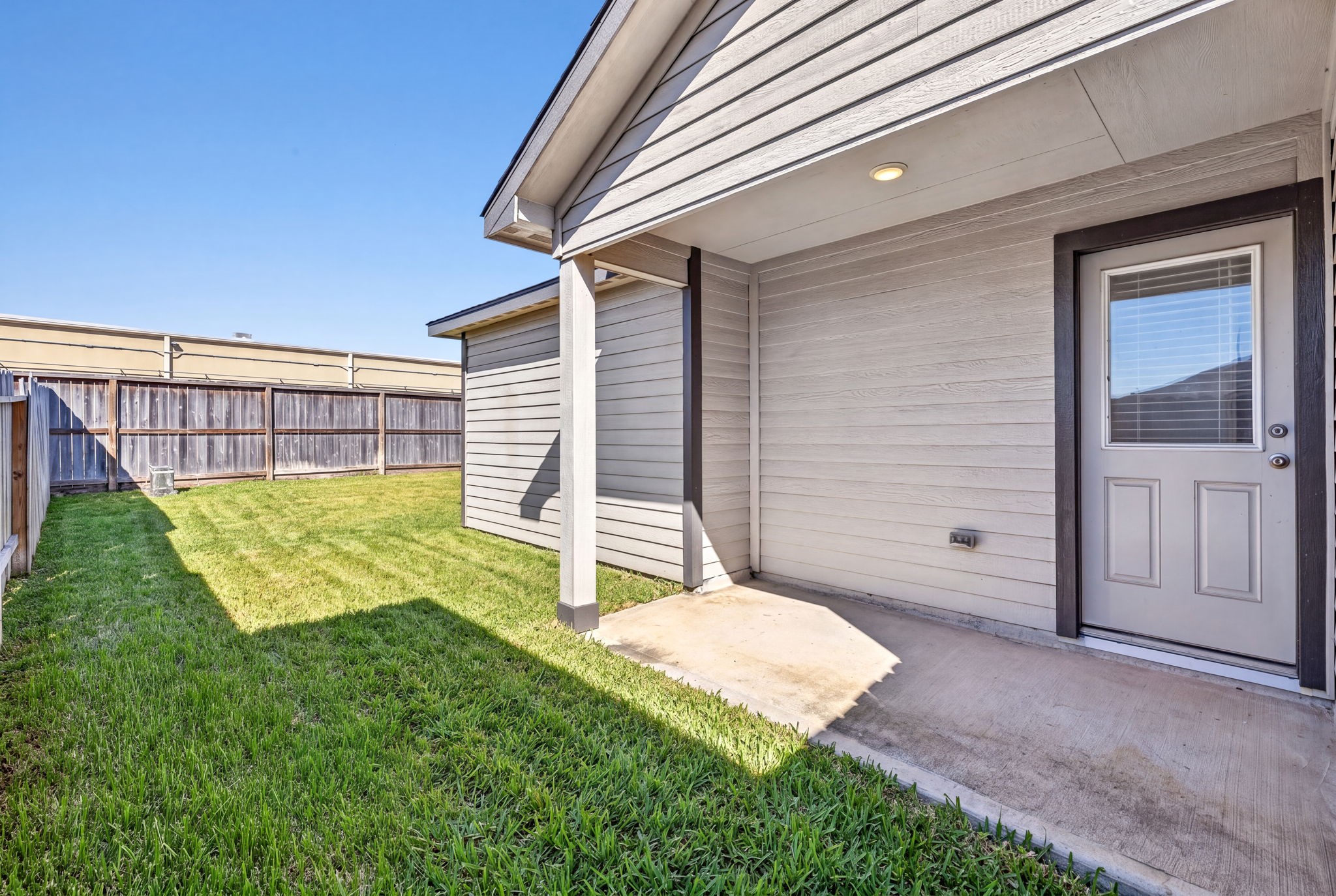 BACKYARD - A covered back patio with an overhead light, a perfect spot for morning coffee or evening grilling.