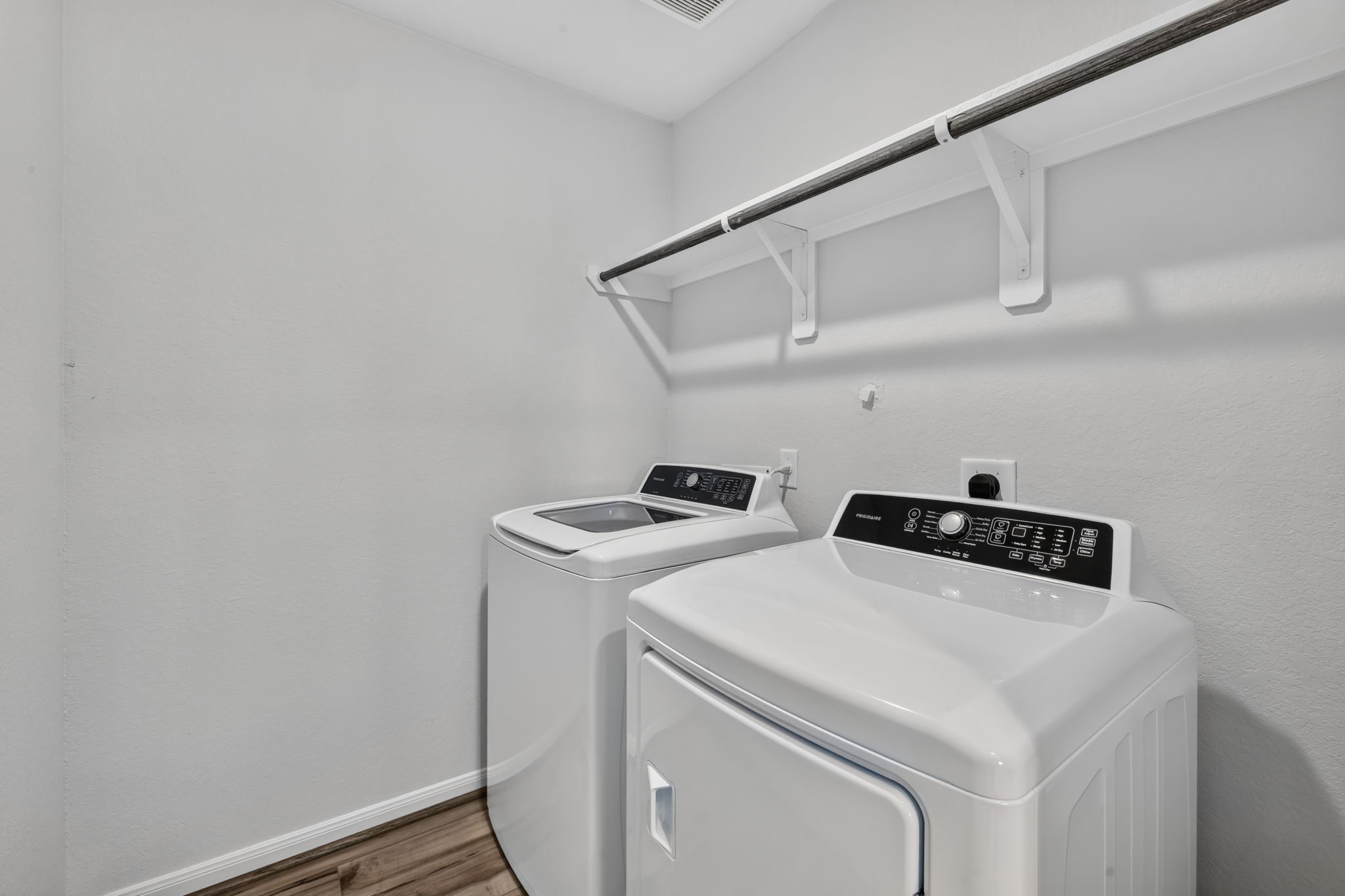 LAUNDRY ROOM - A dedicated laundry room with a hanging rod and shelf, room for a full-size washer and dryer located near the primary bedroom.
