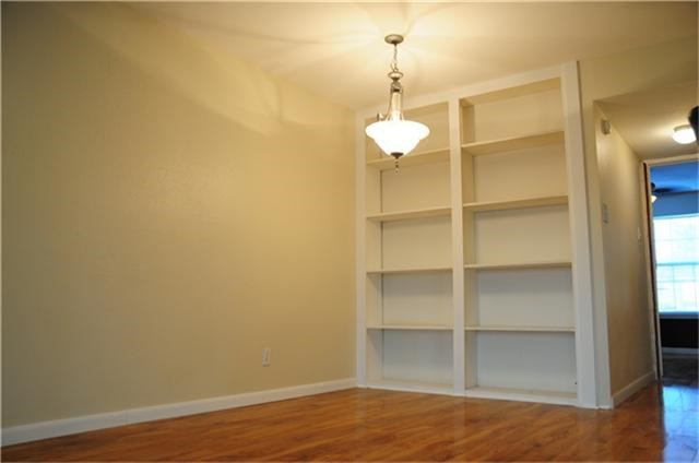 This room features hardwood floors, a built-in bookshelf, and a chandelier, offering a cozy and functional space.