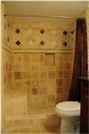 This bathroom features warm-toned, tiled walls with decorative accents, a shower curtain, and a white toilet. It offers a cozy, classic feel.
