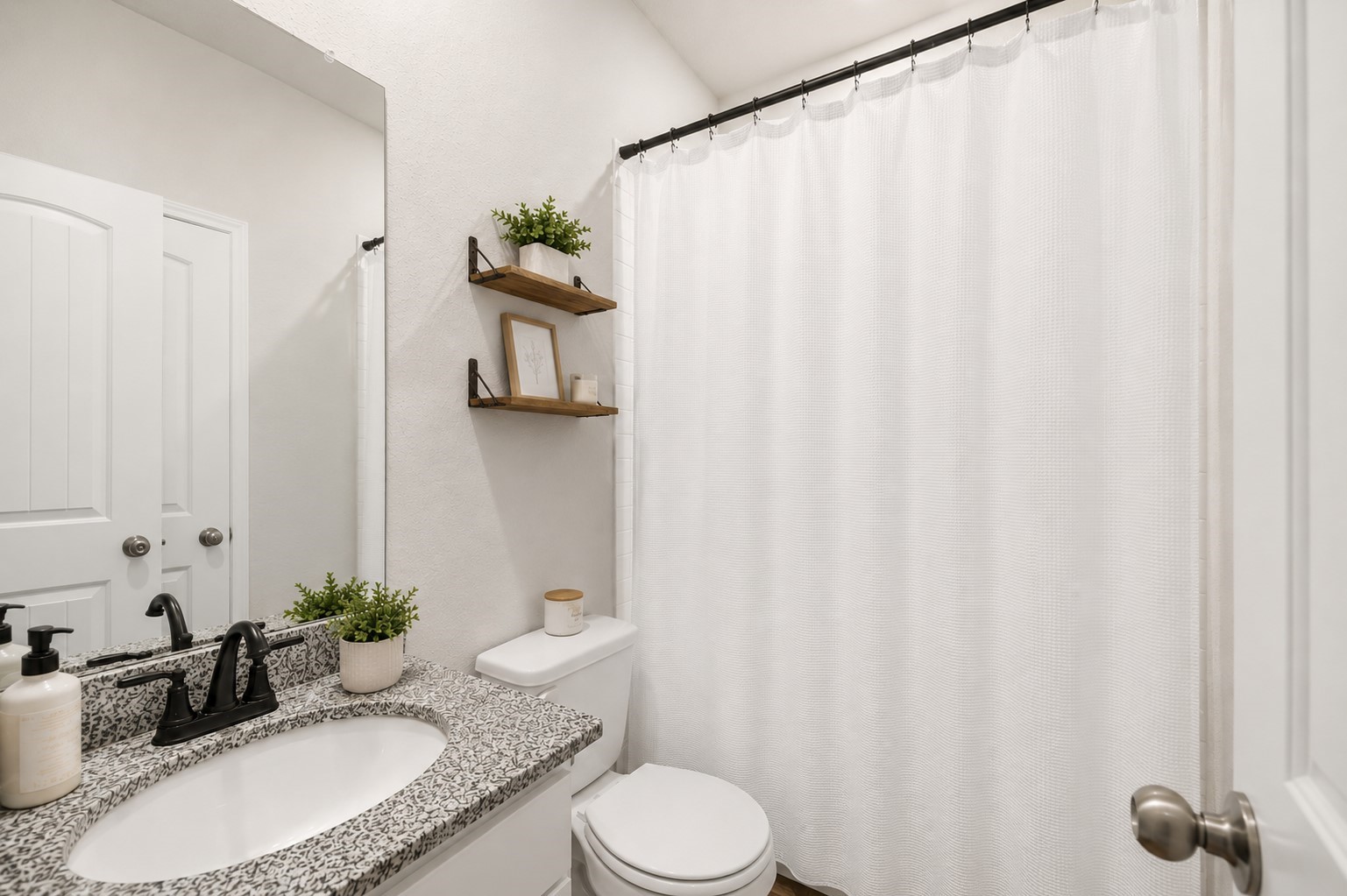Charming 1st floor full bathroom featuring a sleek granite countertop, modern fixtures, and stylish floating shelves