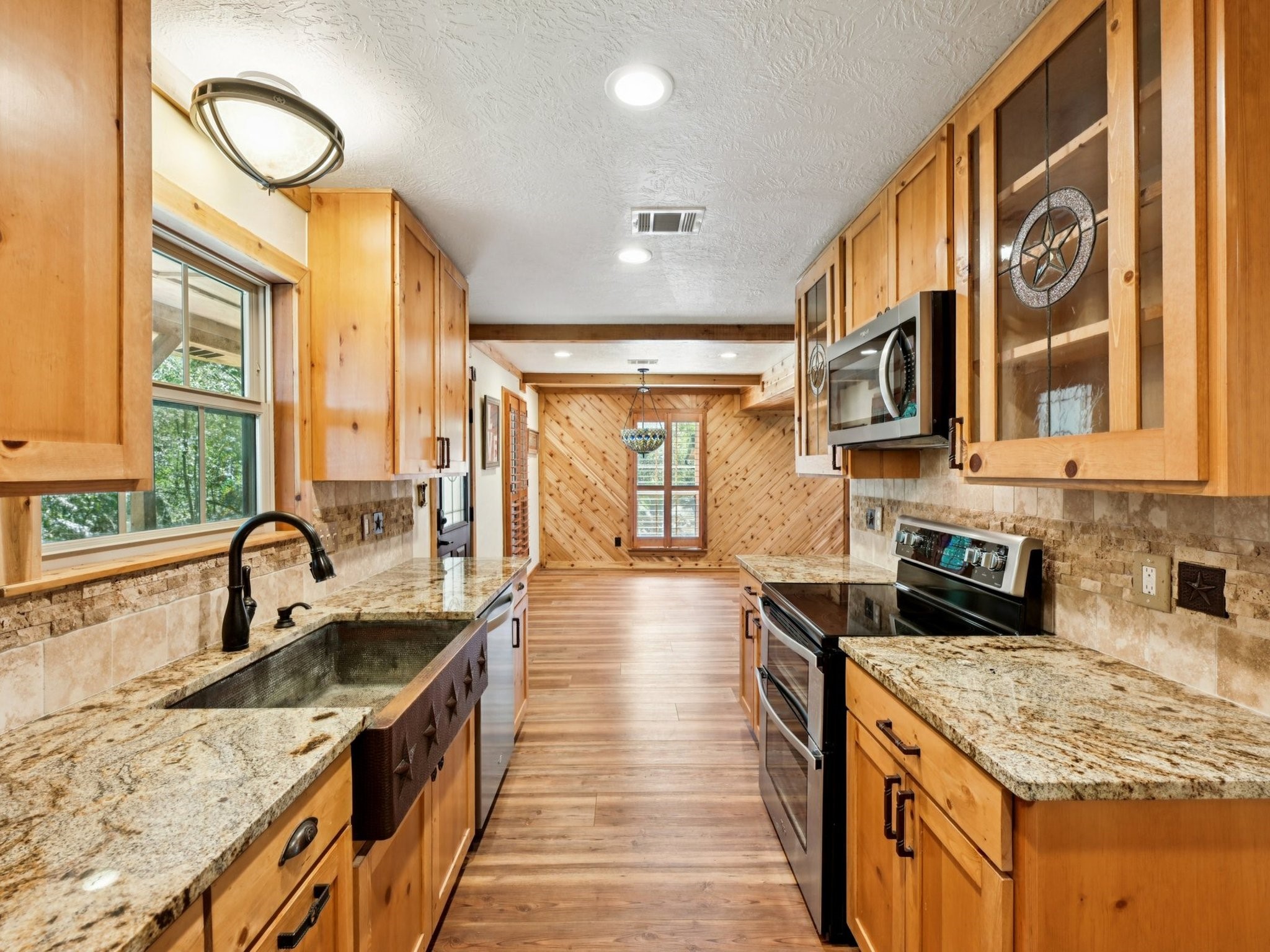 The copper farmhouse sink and custom wood cabinetry, with some glass doors, add to the charm of this Kitchen.
