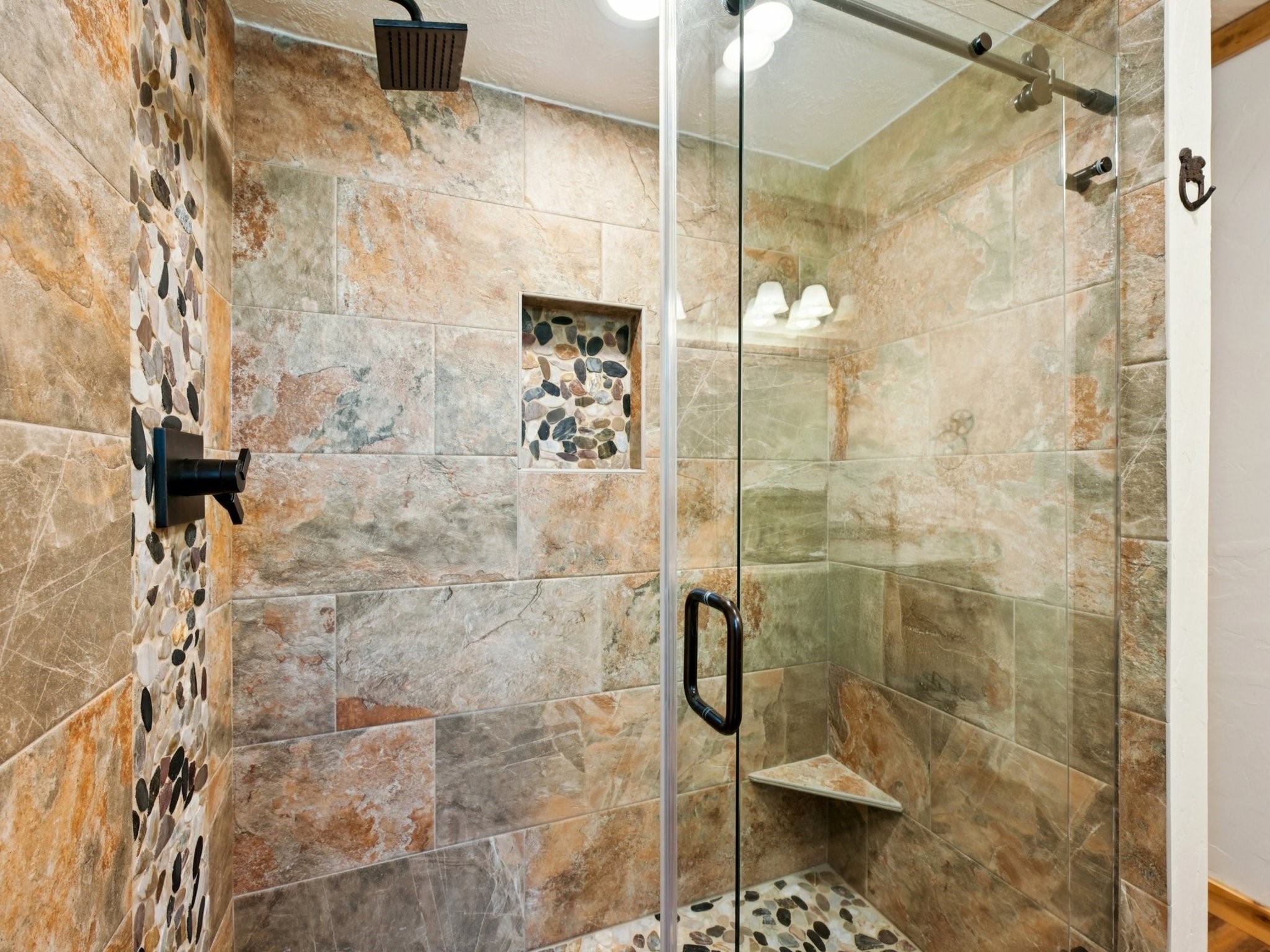 The shower has a pretty river rock floor and inlay with shampoo niche.