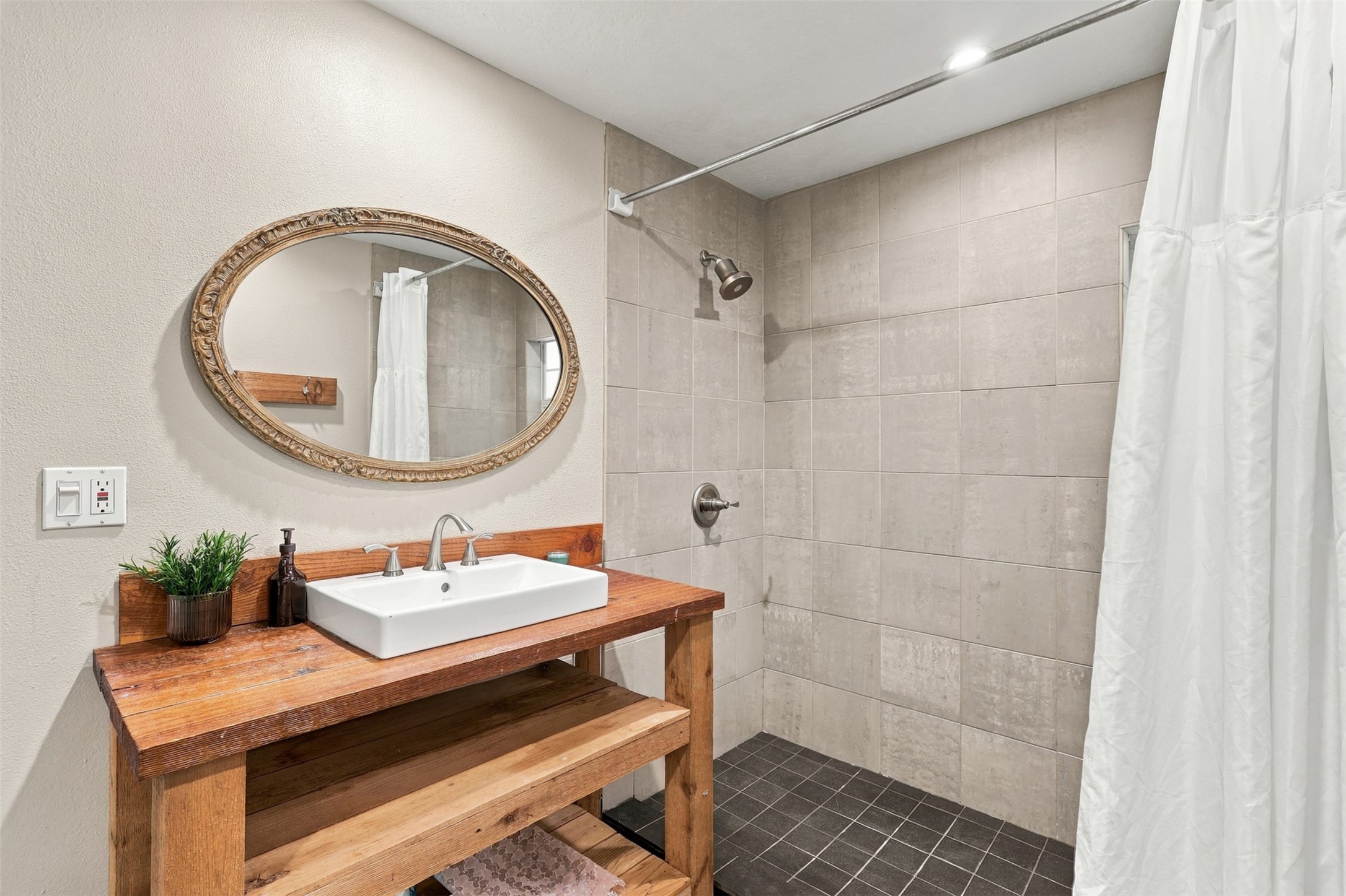 Charming bathroom with a rustic wooden vanity, stylish vessel sink, and a spacious tiled walk-in shower.