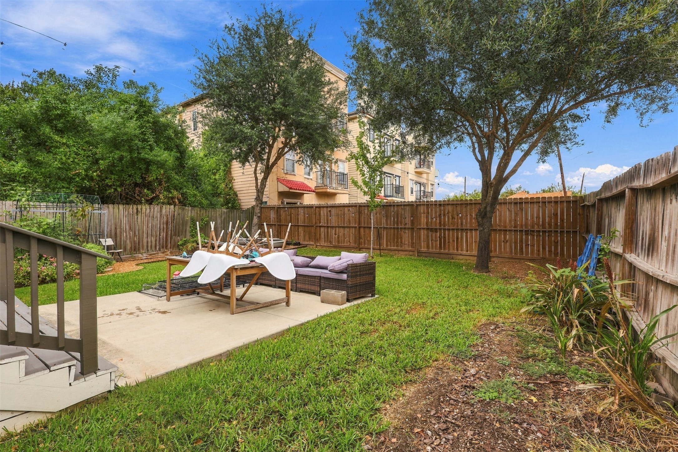 Charming backyard with lush greenery, a cozy patio area, and mature trees, perfect for outdoor relaxation and entertainment.