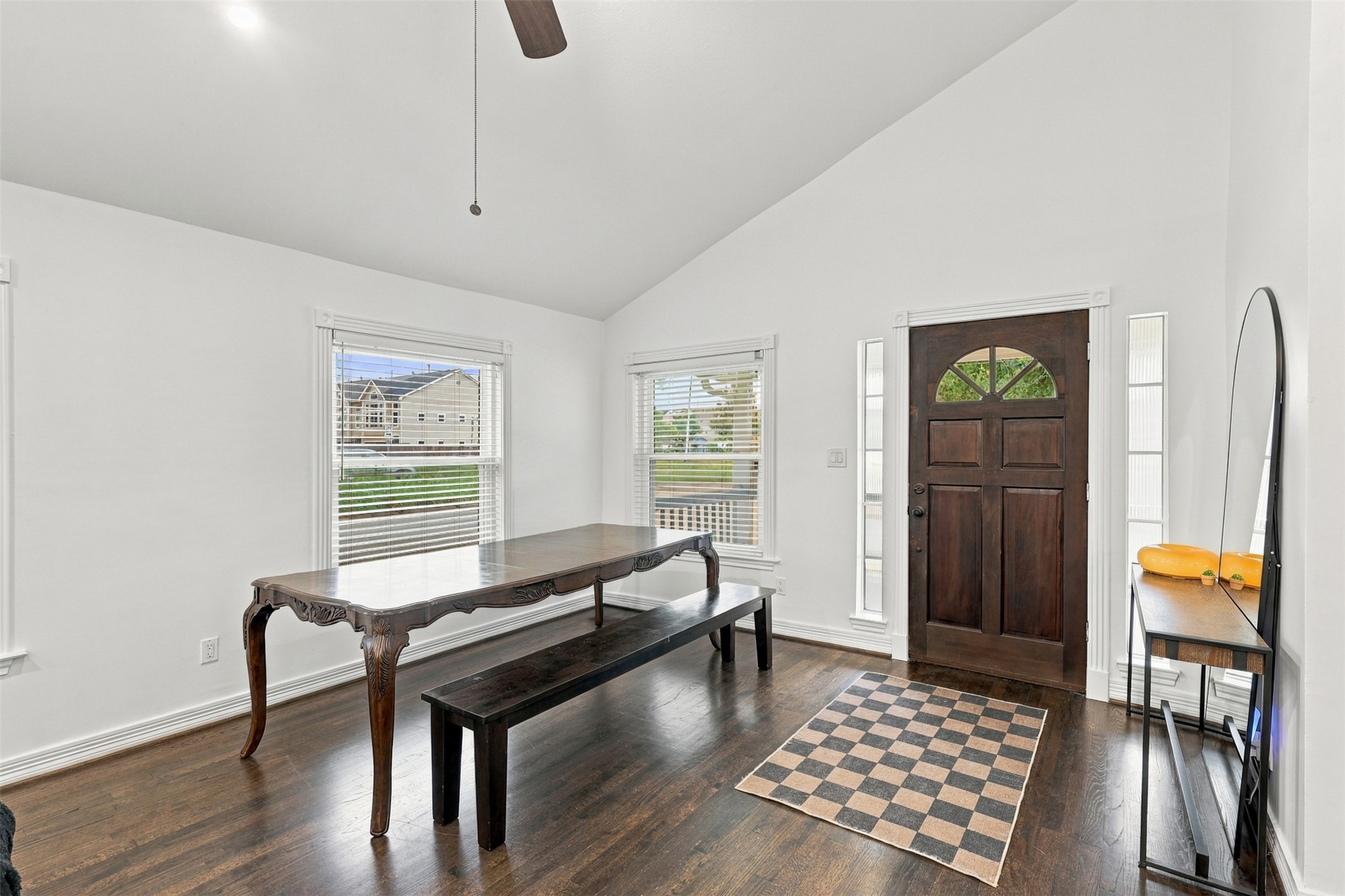 Bright entryway with high ceilings, showcasing a classic wooden door and expansive windows that fill the space with natural light.