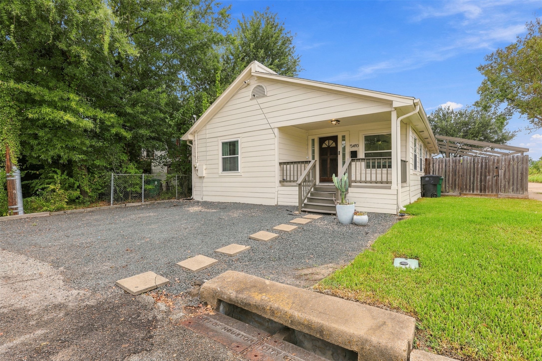 Charming single-story home with a welcoming front porch, nestled on a spacious lot with mature trees and a neatly maintained yard.