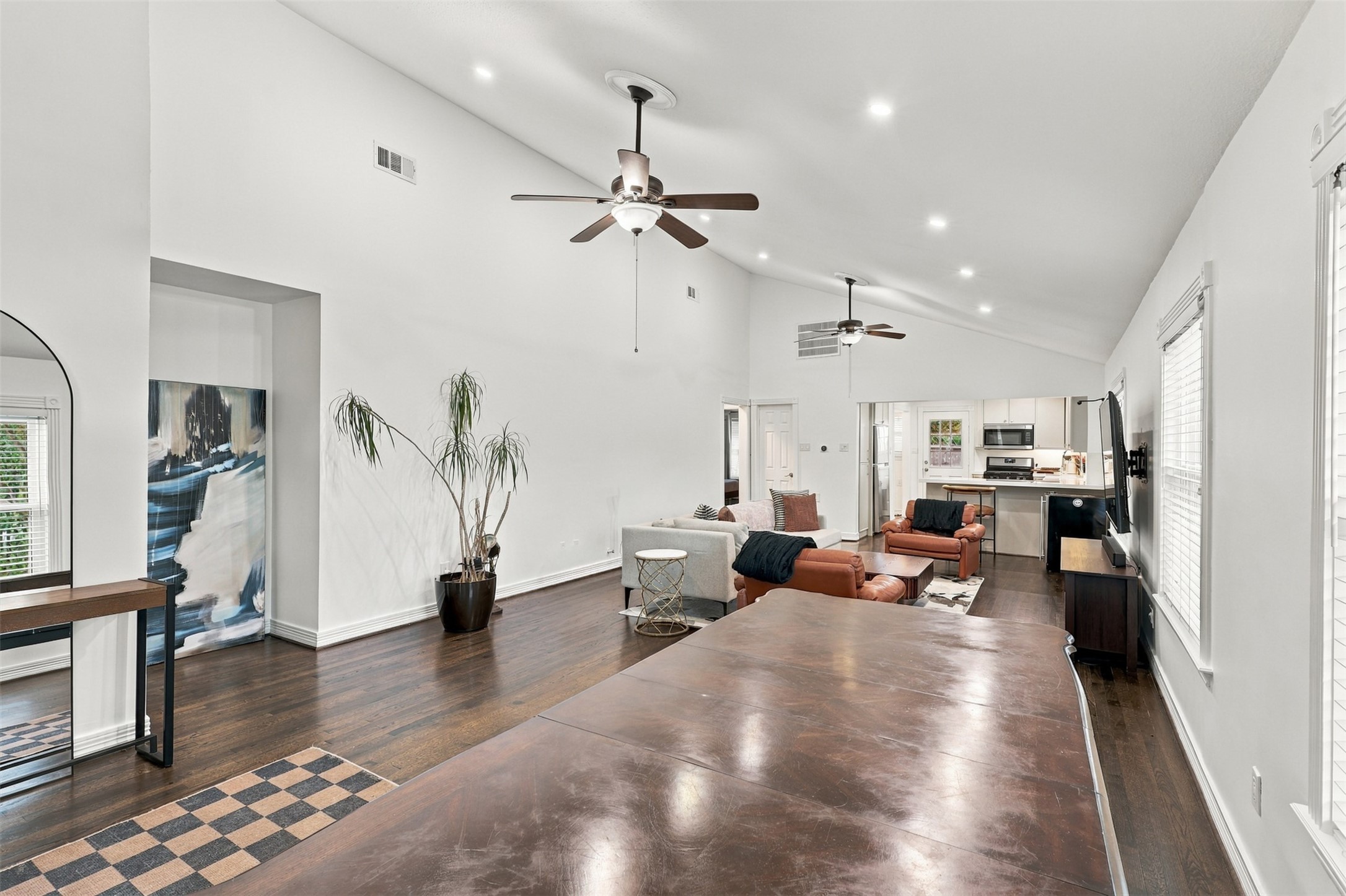 Spacious open-concept living area with high ceilings, elegant hardwood floors, and abundant natural light, seamlessly flowing into a modern kitchen.