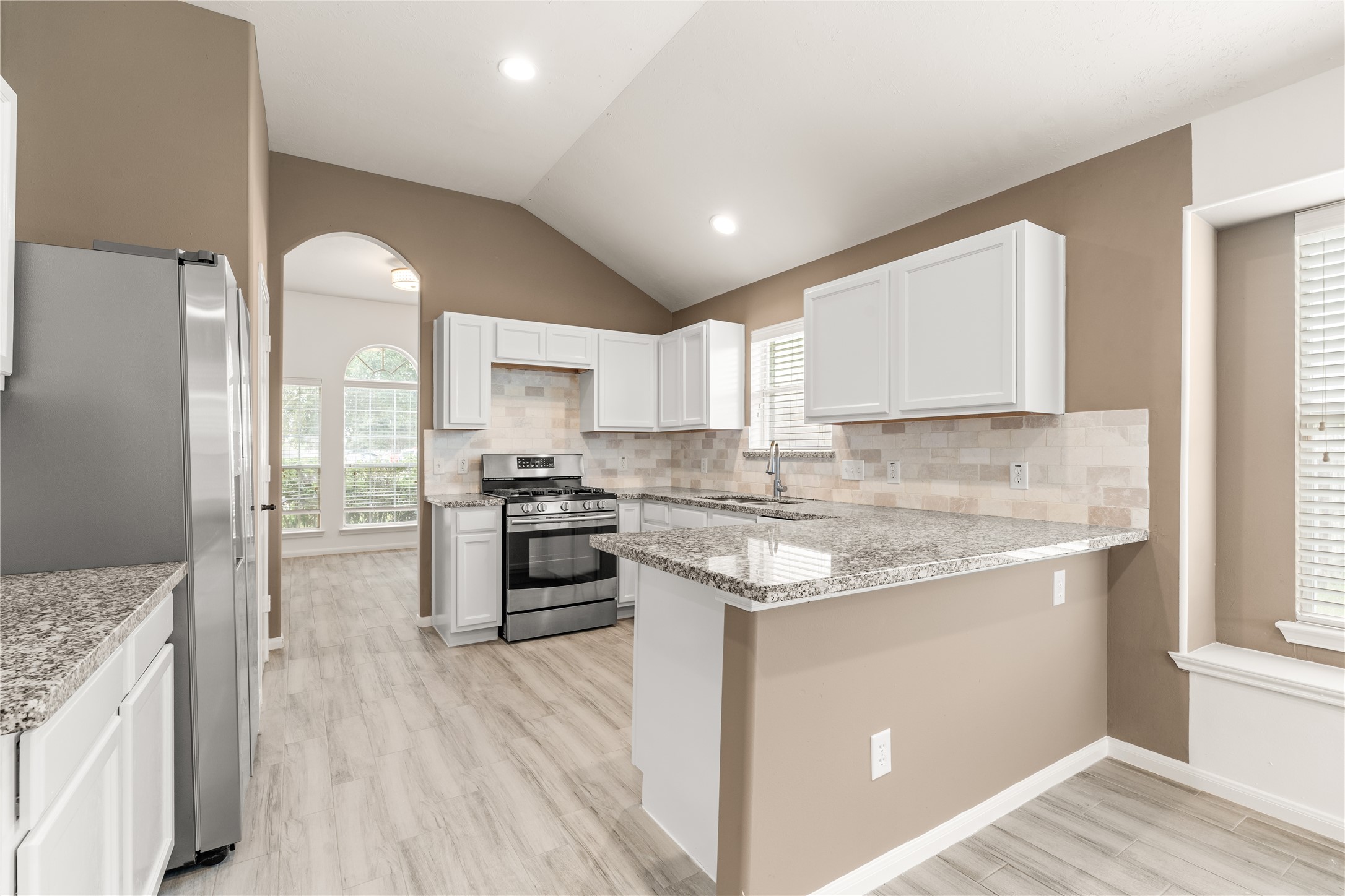 Beautifully updated kitchen featuring white cabinetry, granite countertops, and a modern stone backsplash.