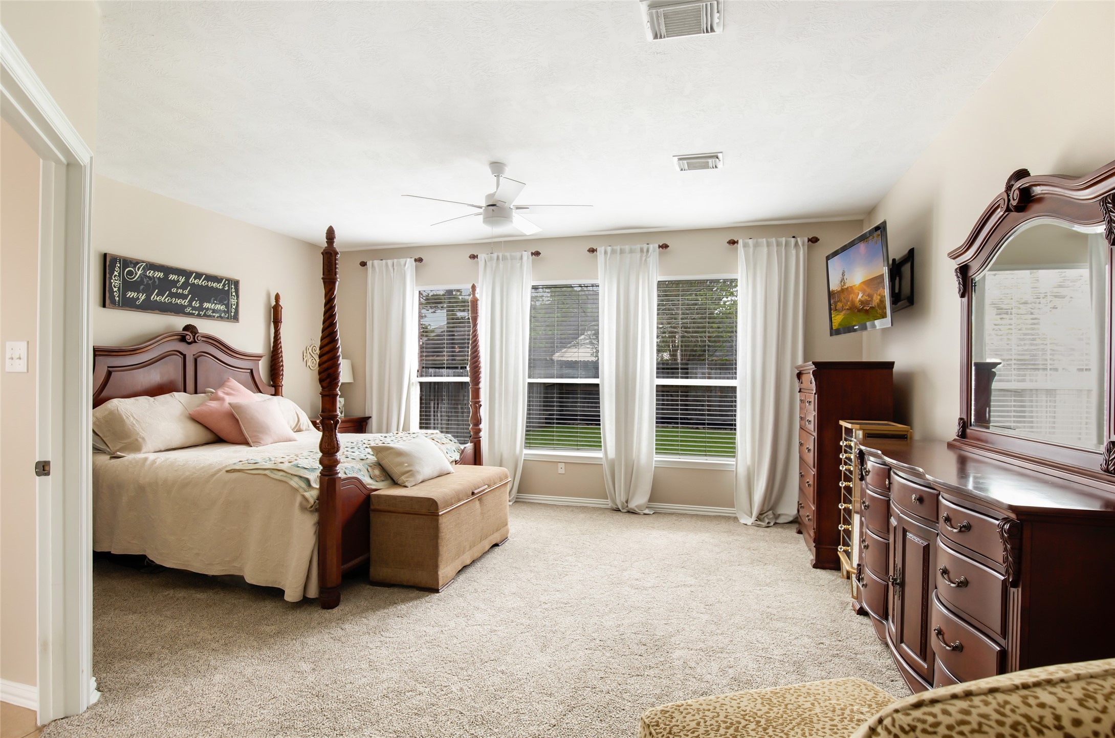 Spacious primary bedroom featuring plush carpeting and abundant natural light