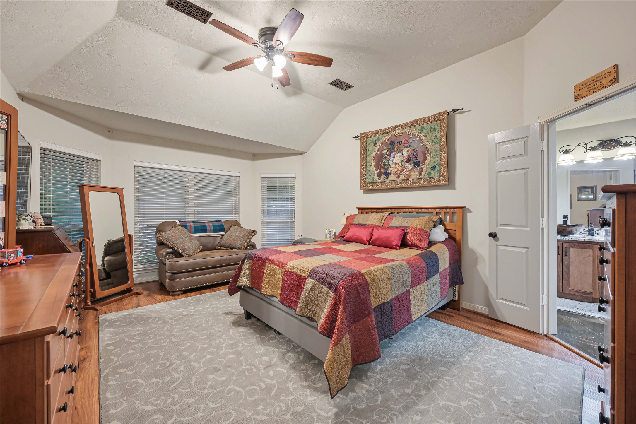 Primary bedroom with bay windows, laminate floors, fan with light kit and beautiful en-suite bathroom