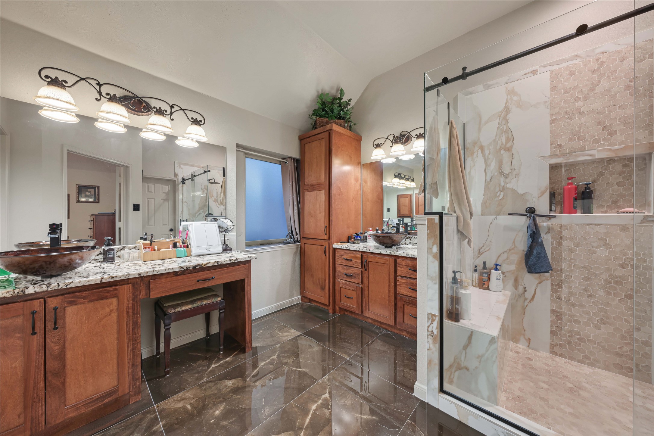 Primary bathroom with oversized shower with bench, custom cabinets, and glamorous oversized tile floors