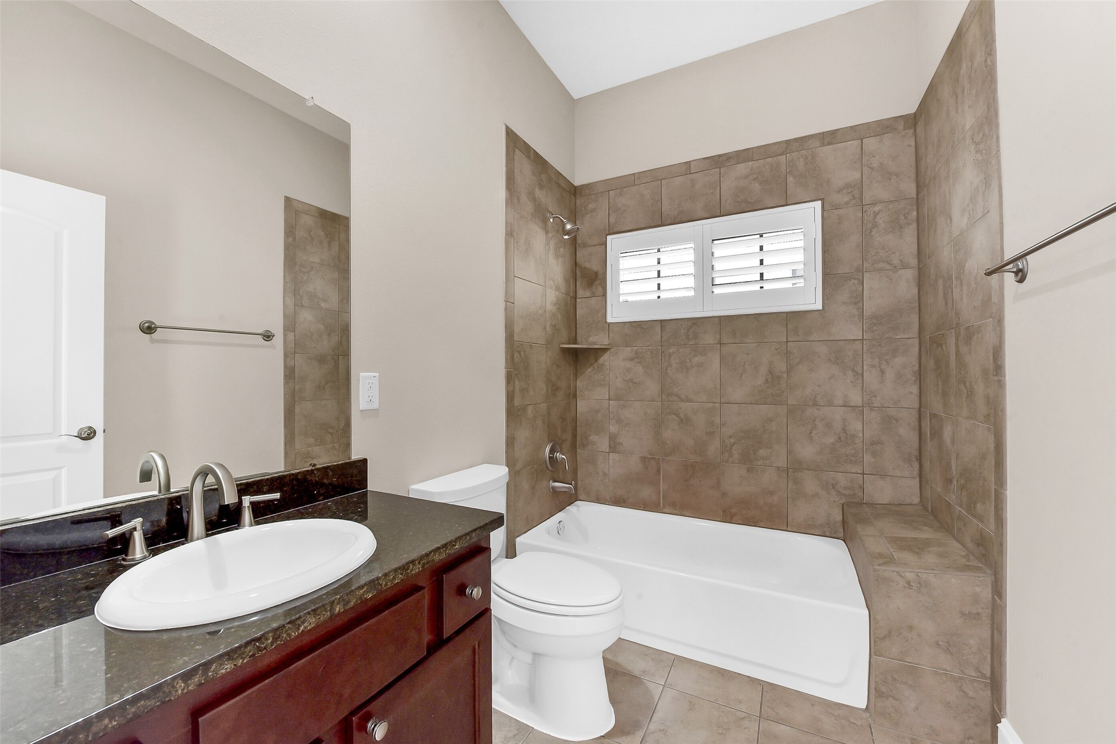 Bathroom has tub/shower combination with tile surround and granite countertops.