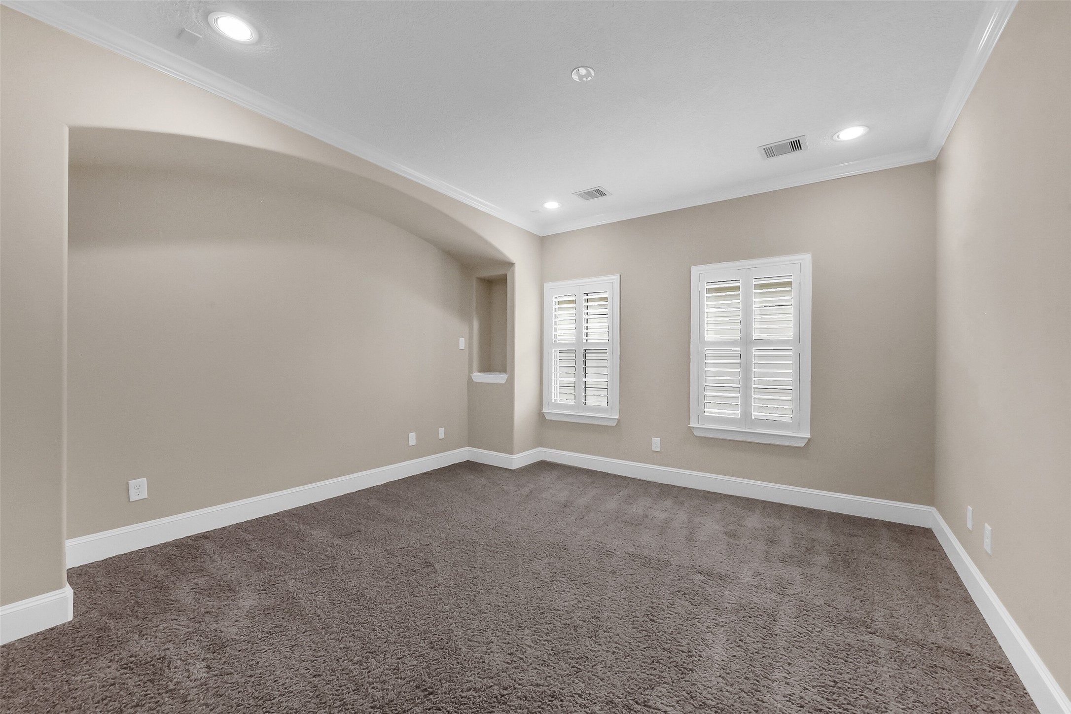 Tuck the bed into this recessed sleeping area in the primary bedroom.  The room also has decorative niche and windows enhanced with Sunburst shutters.