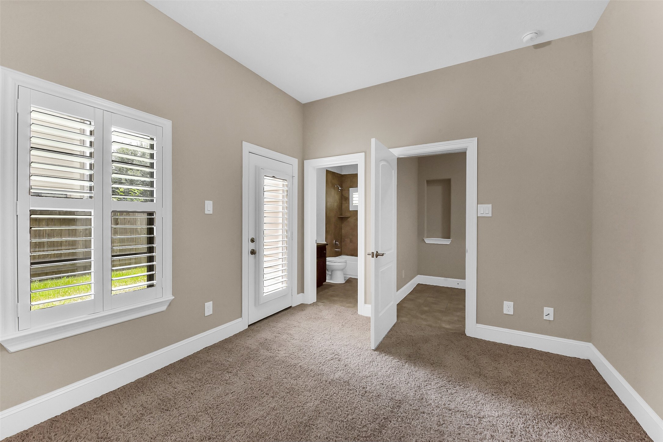 Additional view of the first floor bedroom showing access to the en-suite bathroom and the backyard.  This room would also make a great office.