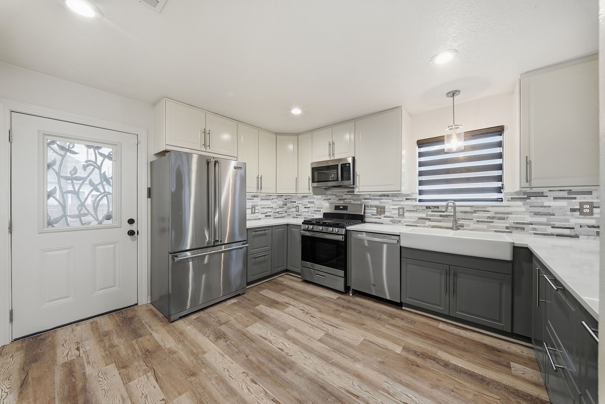 Bright, modern kitchen featuring stainless steel appliances, granite countertops, and a farmhouse-style sink.
