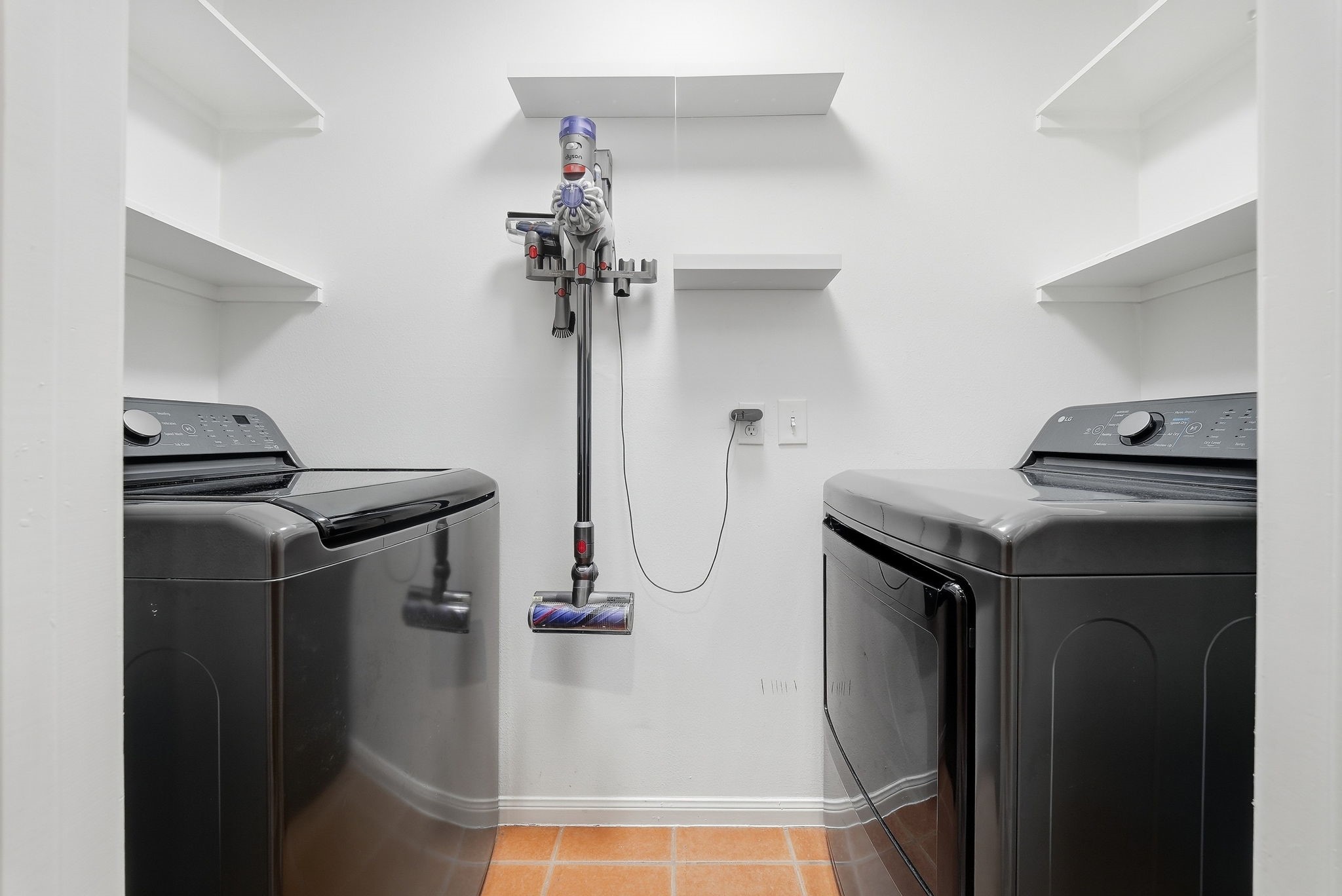 Utility room featuring washer and dryer with built-in storage shelving.