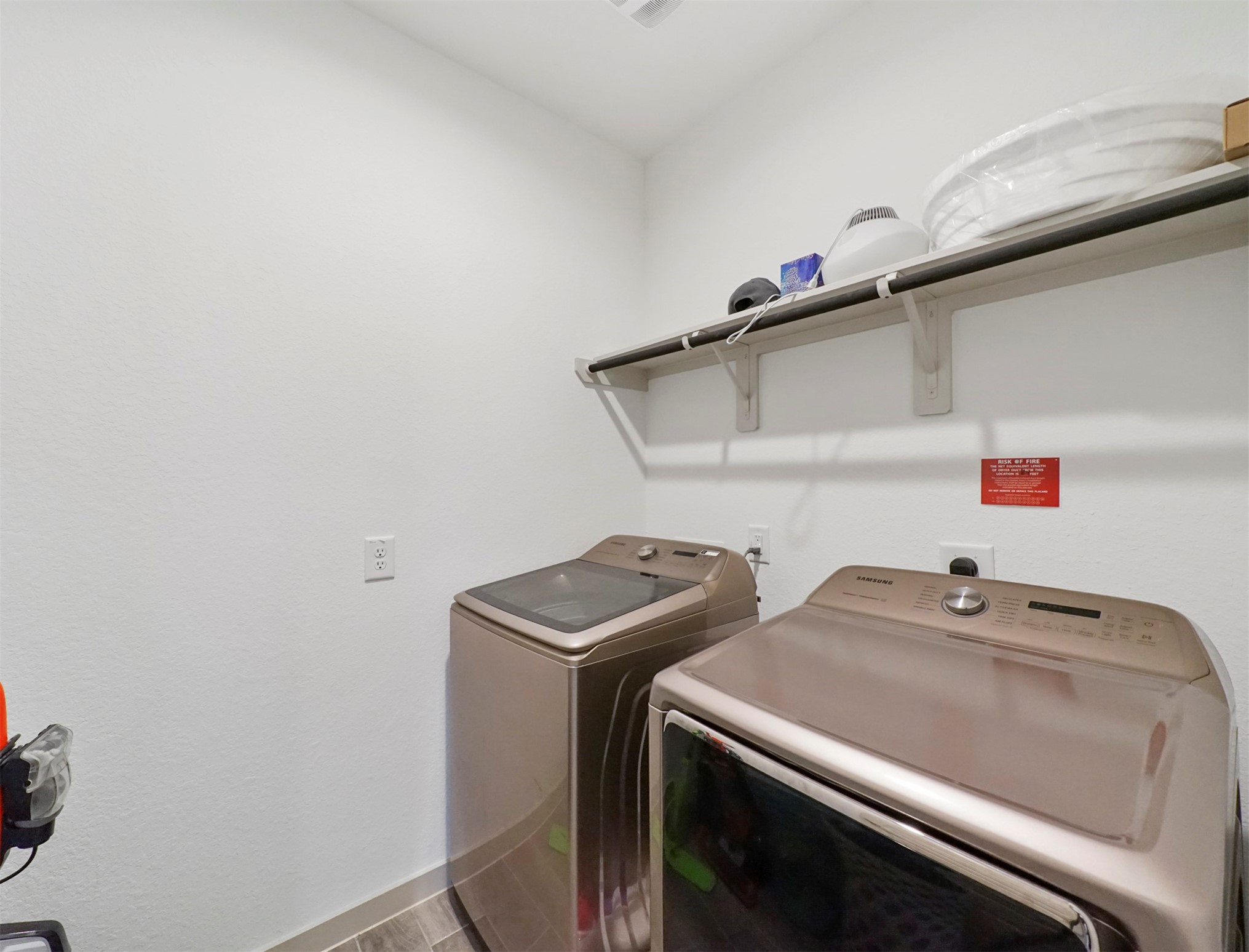 The dedicated laundry room keeps chores organized, with washer and dryer connections and a built-in shelf with a hanging rod for folding and drying.