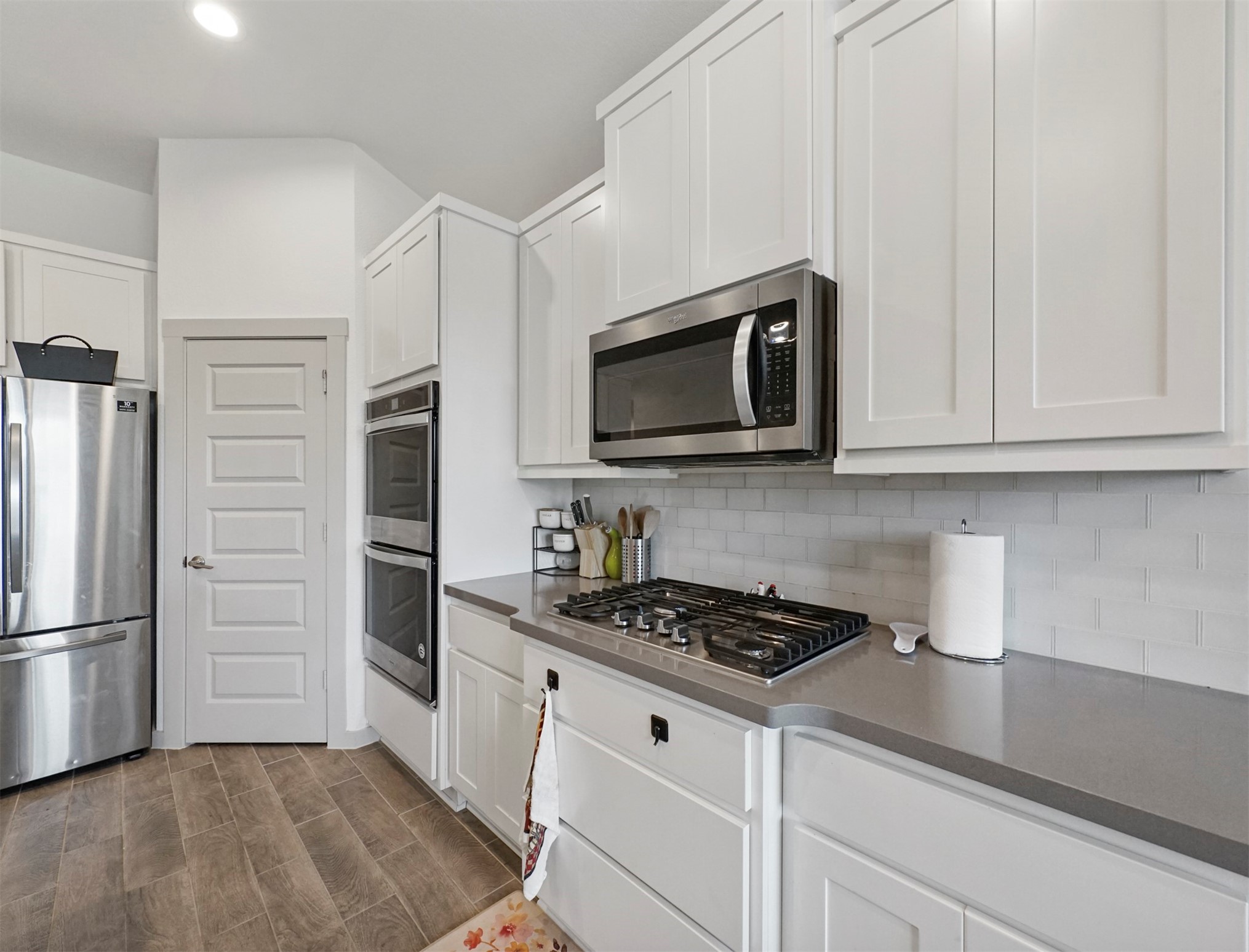 A gas cooktop sits beneath a built-in microwave, framed by a white subway tile backsplash and generous cabinet storage.