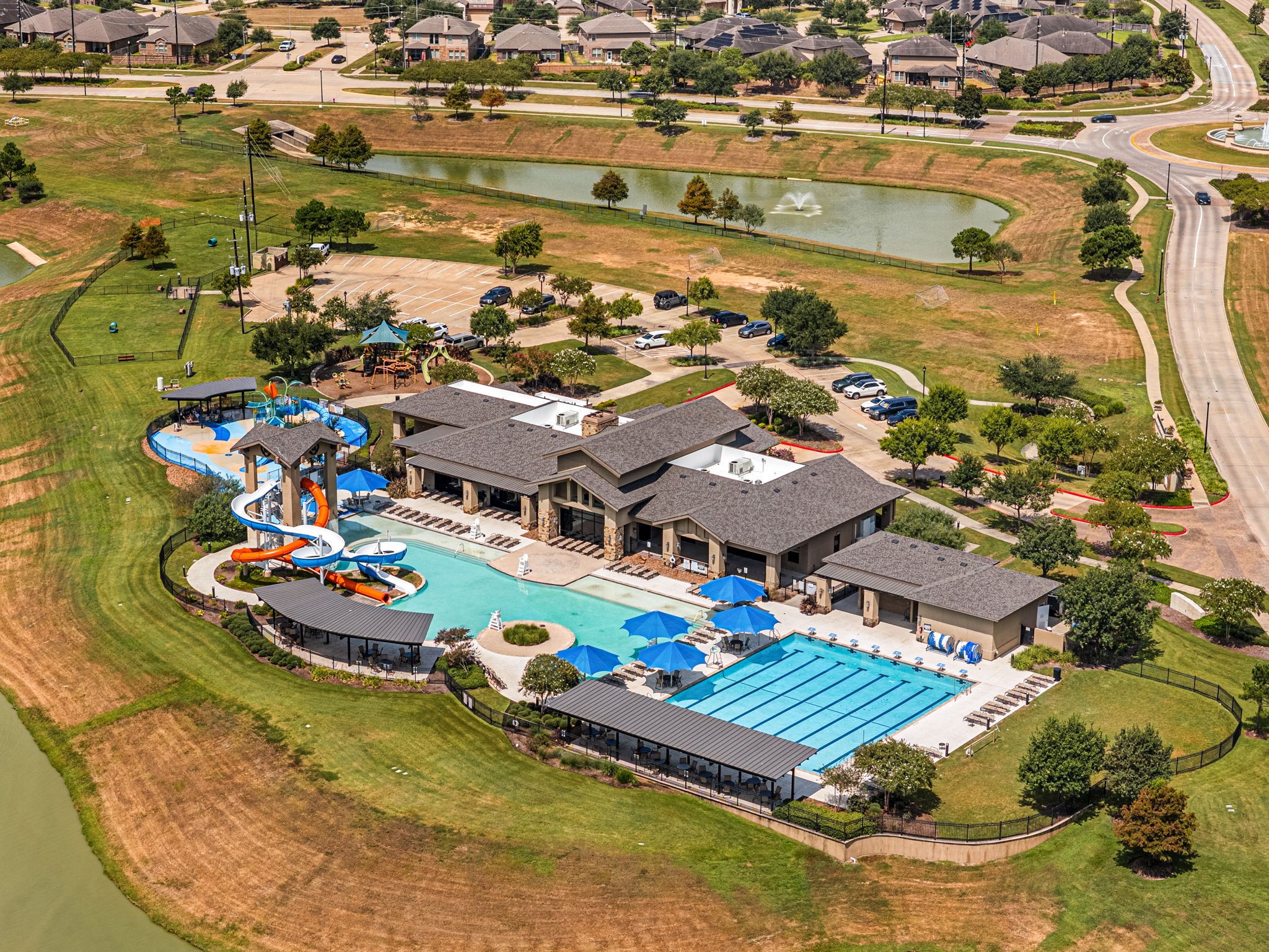Tamarrons resort-style amenity complex features a resort pool with water slides and splash features, a dedicated lap pool, shaded seating areas, and an adjacent playground, offering plenty of ways to swim, play, and spend time outdoors.