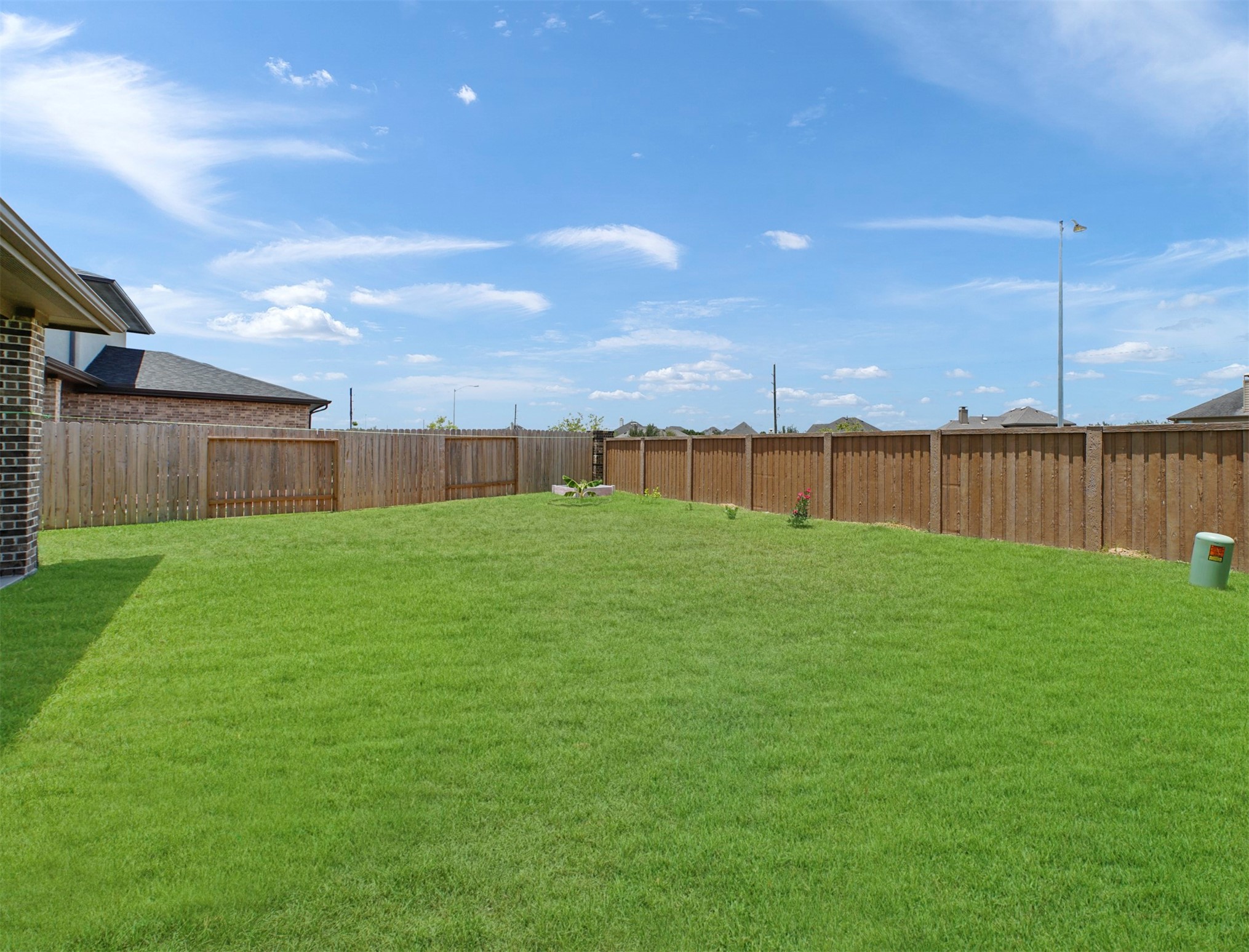 A broad stretch of lawn is enclosed by privacy fencing, leaving plenty of room to garden, relax, or entertain outdoors.