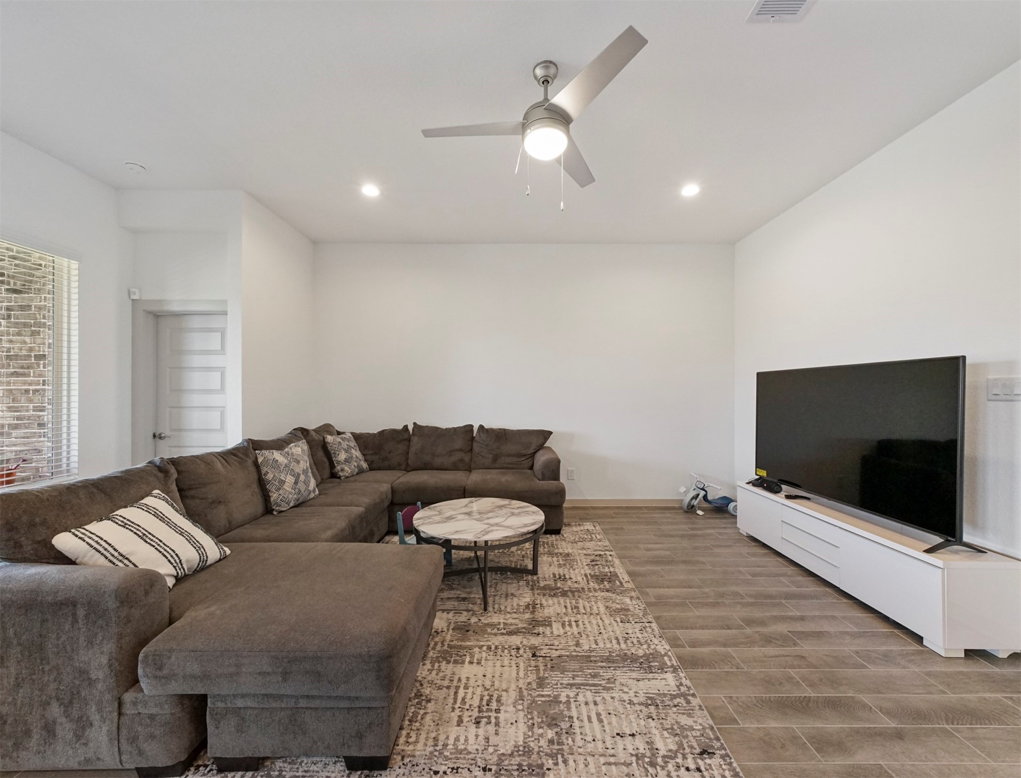 The living room has a ceiling fan with light and a large window, plus plenty of open wall space for flexible furniture placement.