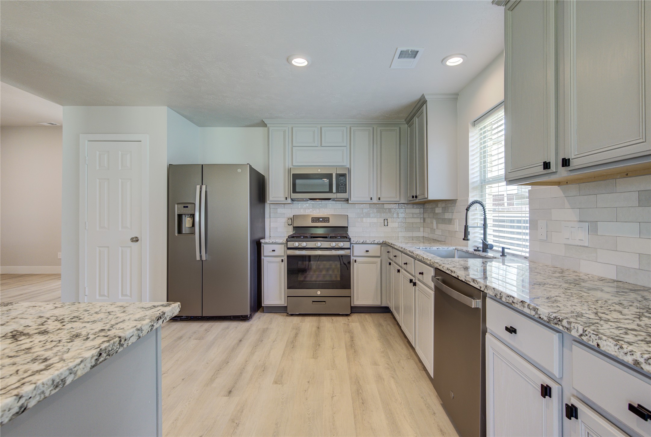 The beautifully renovated kitchen offers abundant cabinet storage, expansive granite countertops, subway tile backsplash and a large breakfast bar perfect for everyday living and entertaining