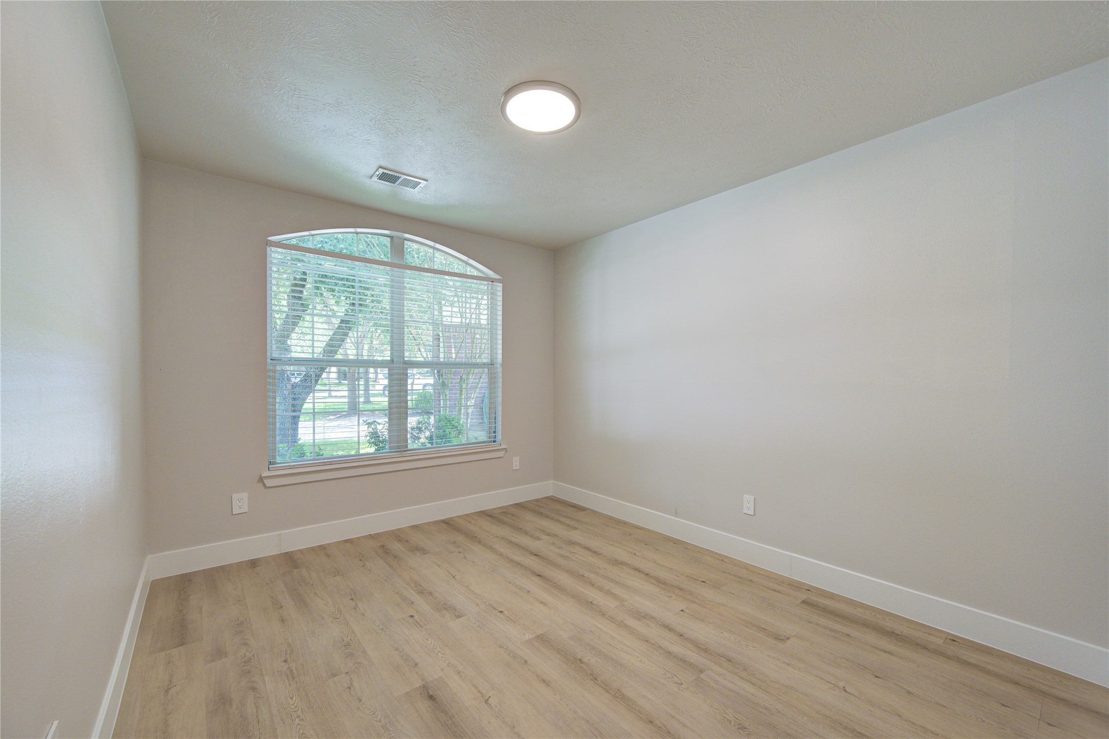 Relax in the spacious secondary bedroom featuring oversized windows, updated luxury vinyl plank flooring