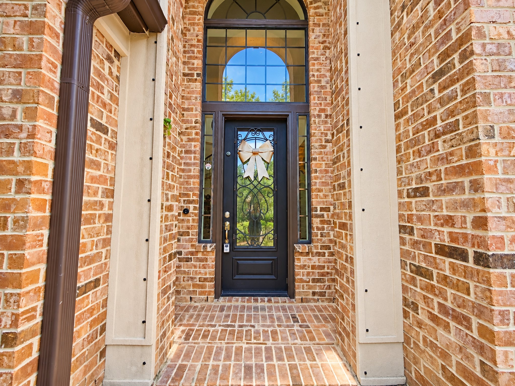 Arched iron-and-glass front door framed in brick.