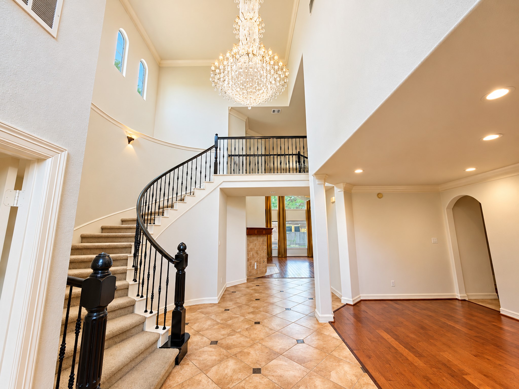 Two-story foyer with curved staircase and crystal chandelier.