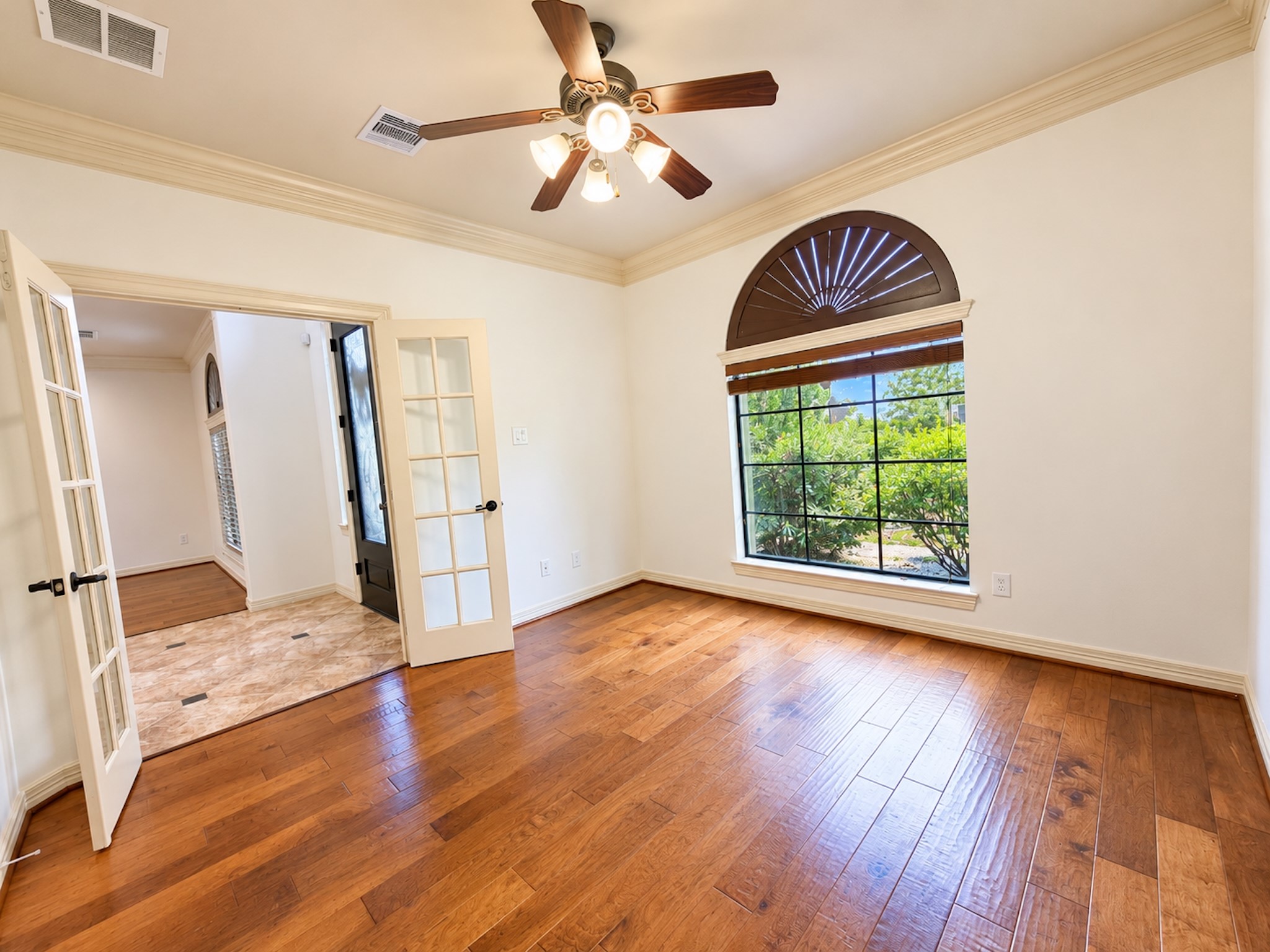 Study with French doors, wood floors and arched window.
