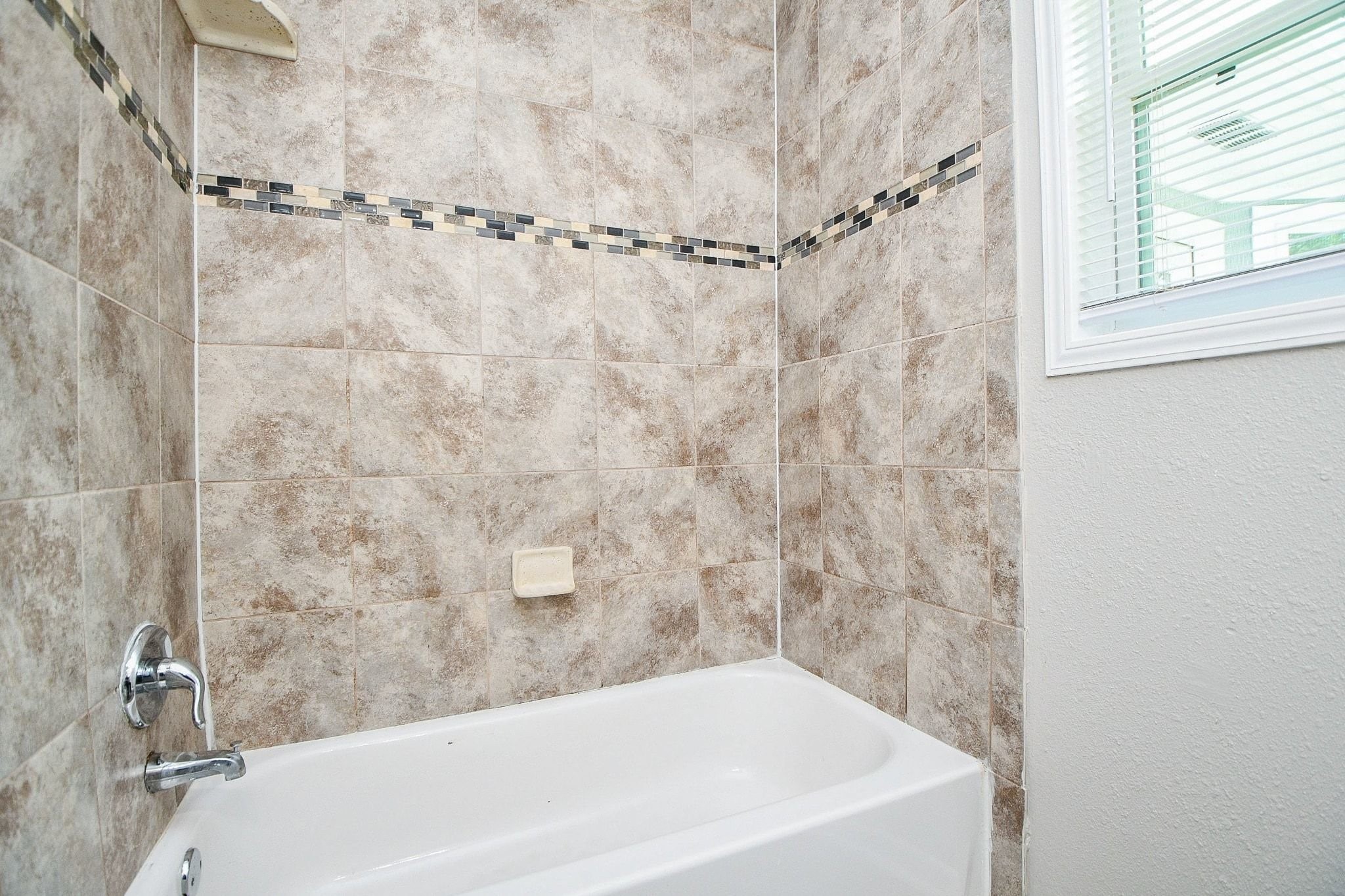 Bath and shower combo with easy to clean tile and accents makes this shower pop.