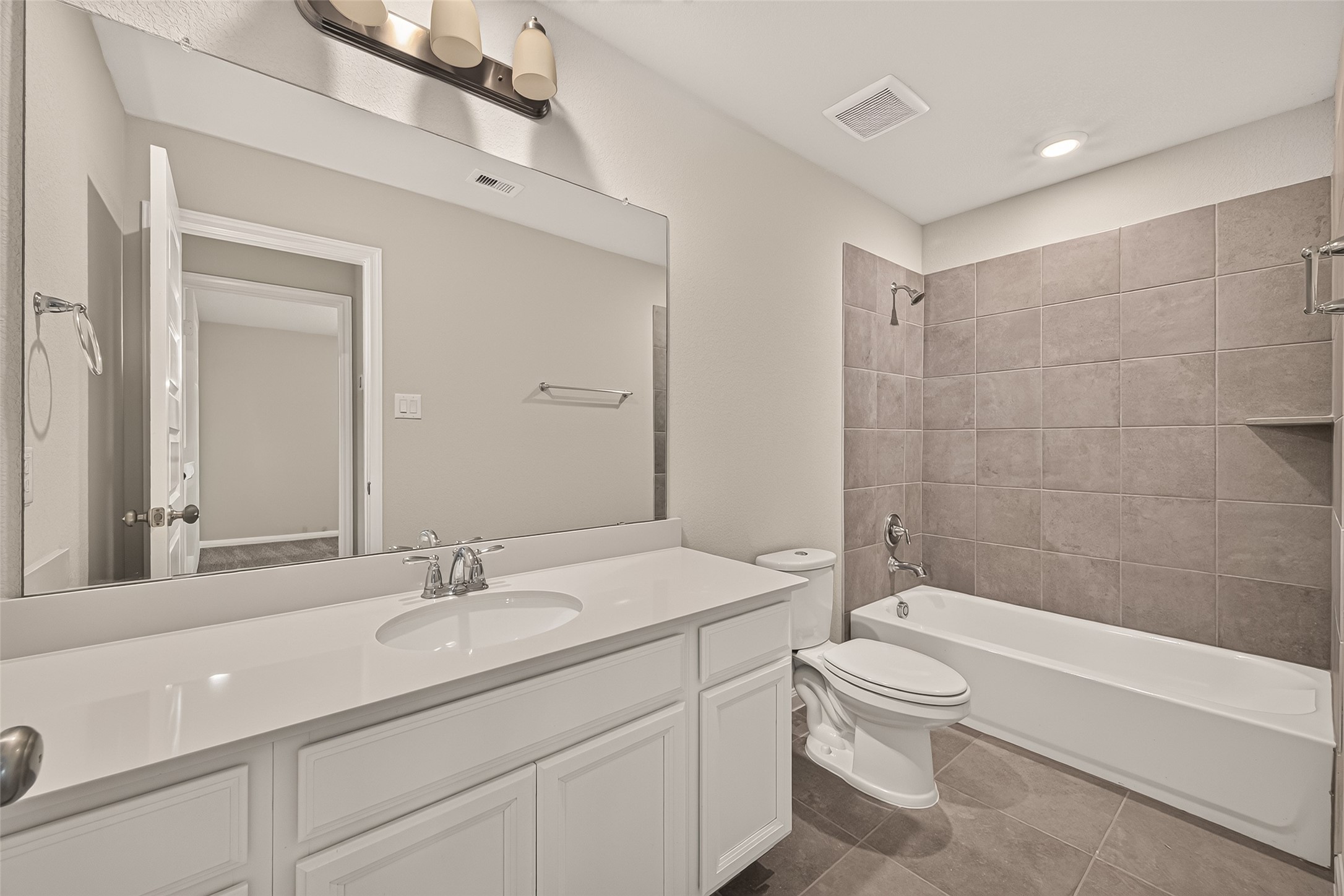 The secondary bathroom offers a modern bathroom featuring a sleek vanity, large mirror, and a shower-tub combo with elegant tilework.