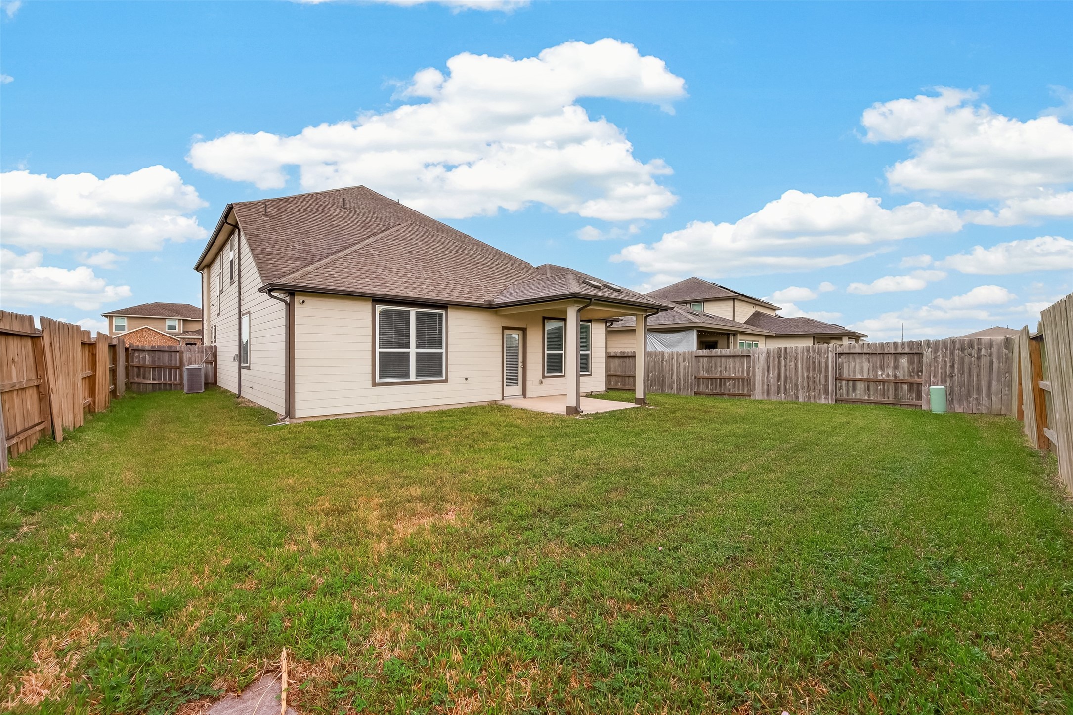 Spacious backyard with a covered patio, perfect for outdoor gatherings and relaxation, surrounded by a wooden privacy fence.
