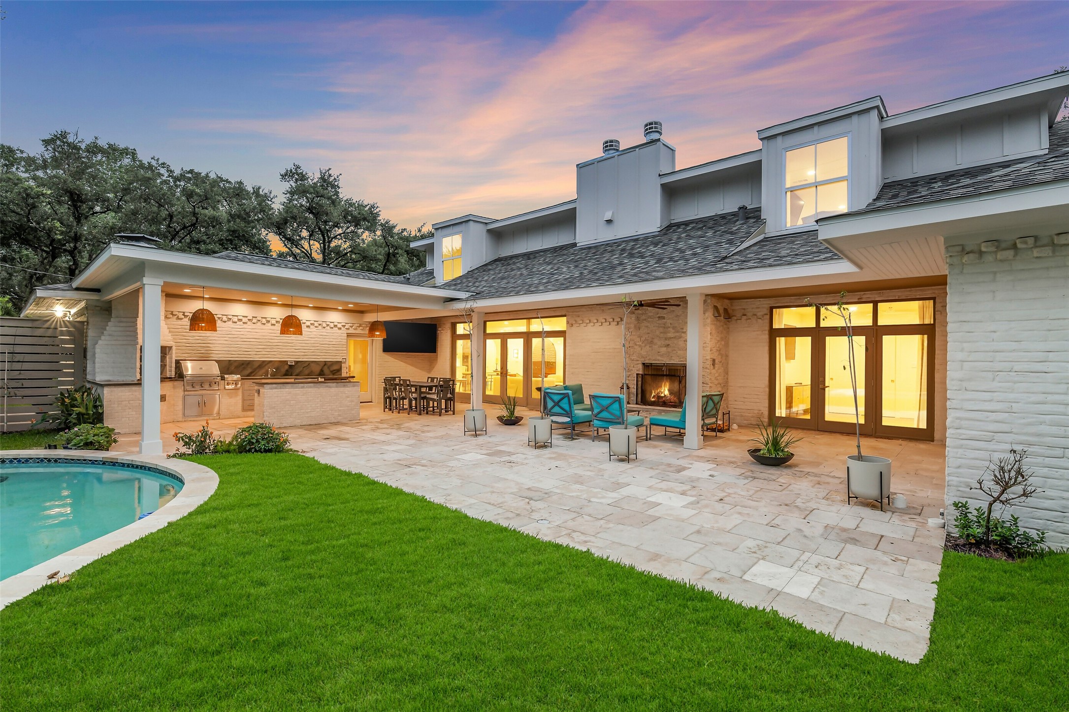 A private, beautifully landscaped backyard featuring a sparkling pool, lush lawn, and covered patio  the perfect setting for relaxing or entertaining outdoors. The home's modern exterior and mature trees complete this serene retreat.