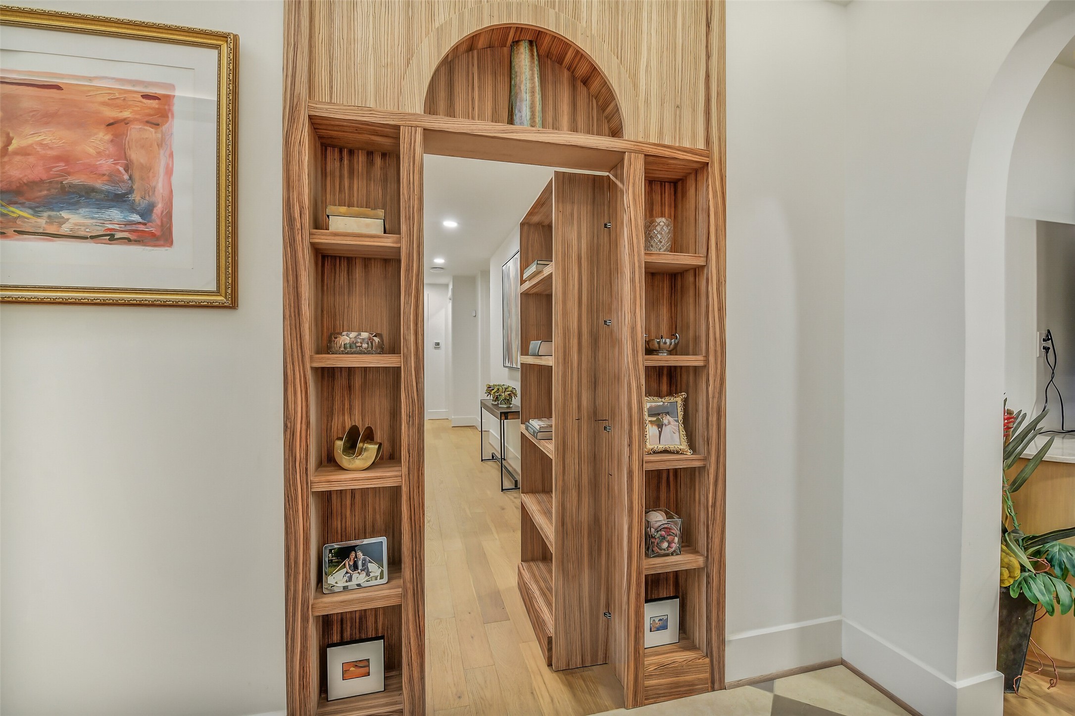 A one-of-a-kind custom rotating wood bookshelf conceals the private bedroom wing, creating a striking hidden doorway that blends craftsmanship, style, and functionality. This unique architectural feature offers an unforgettable transition from the main living spaces to the home's private retreat.