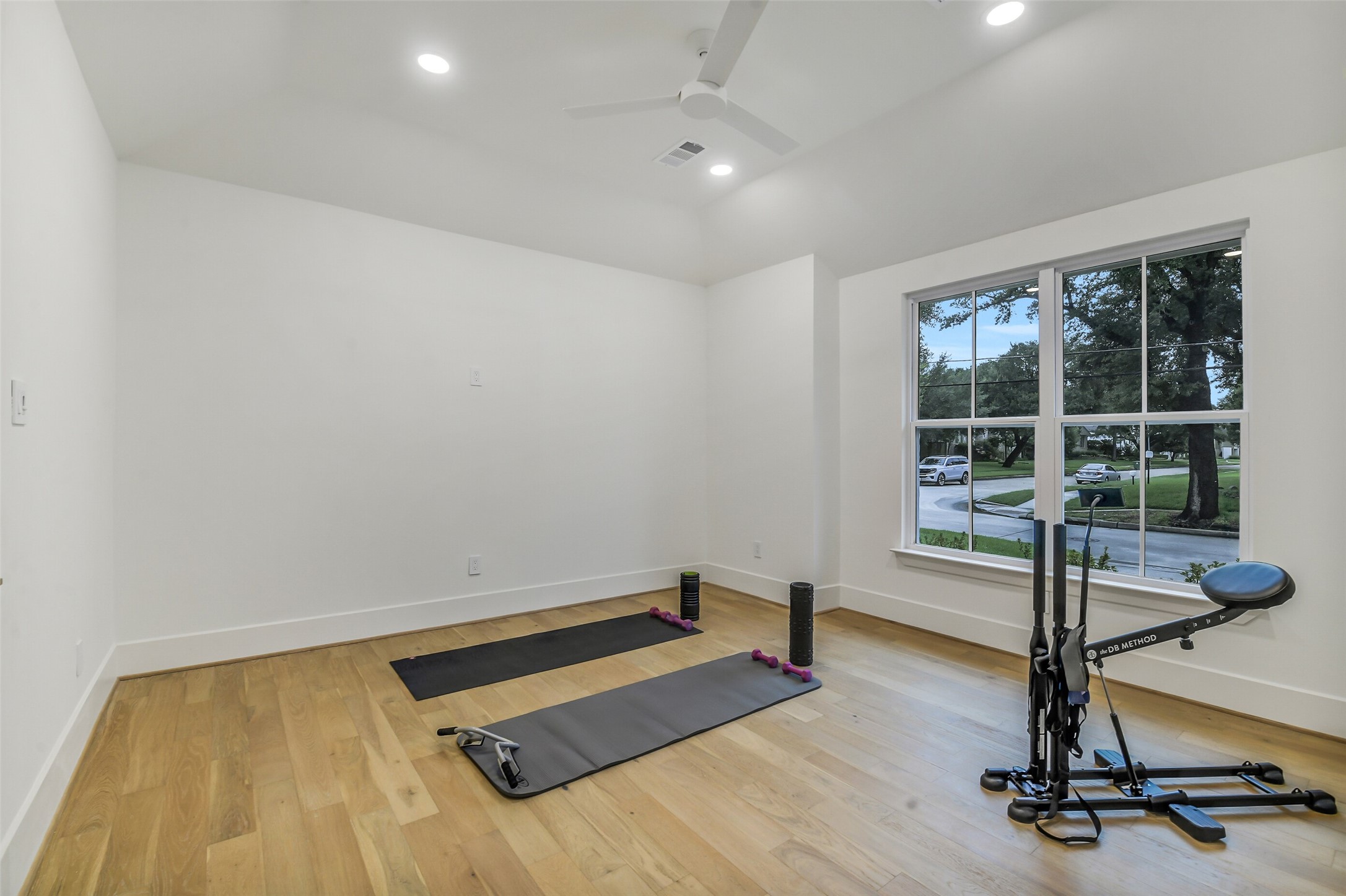 A bright, versatile room with vaulted ceilings, a ceiling fan, and a large window overlooking the front yard. Currently set up as a home gym, this flexible space easily adapts to a playroom, office, or additional living area to suit your needs.