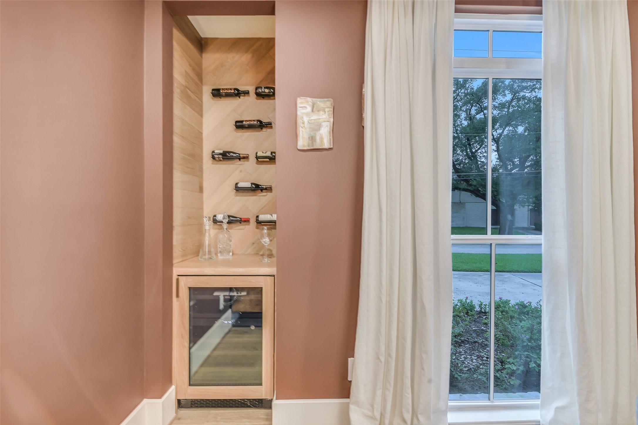 A custom wine display niche with wood-paneled walls and sleek bottle racks sits just off the dining room, complete with a built-in wine fridge for effortless entertaining.