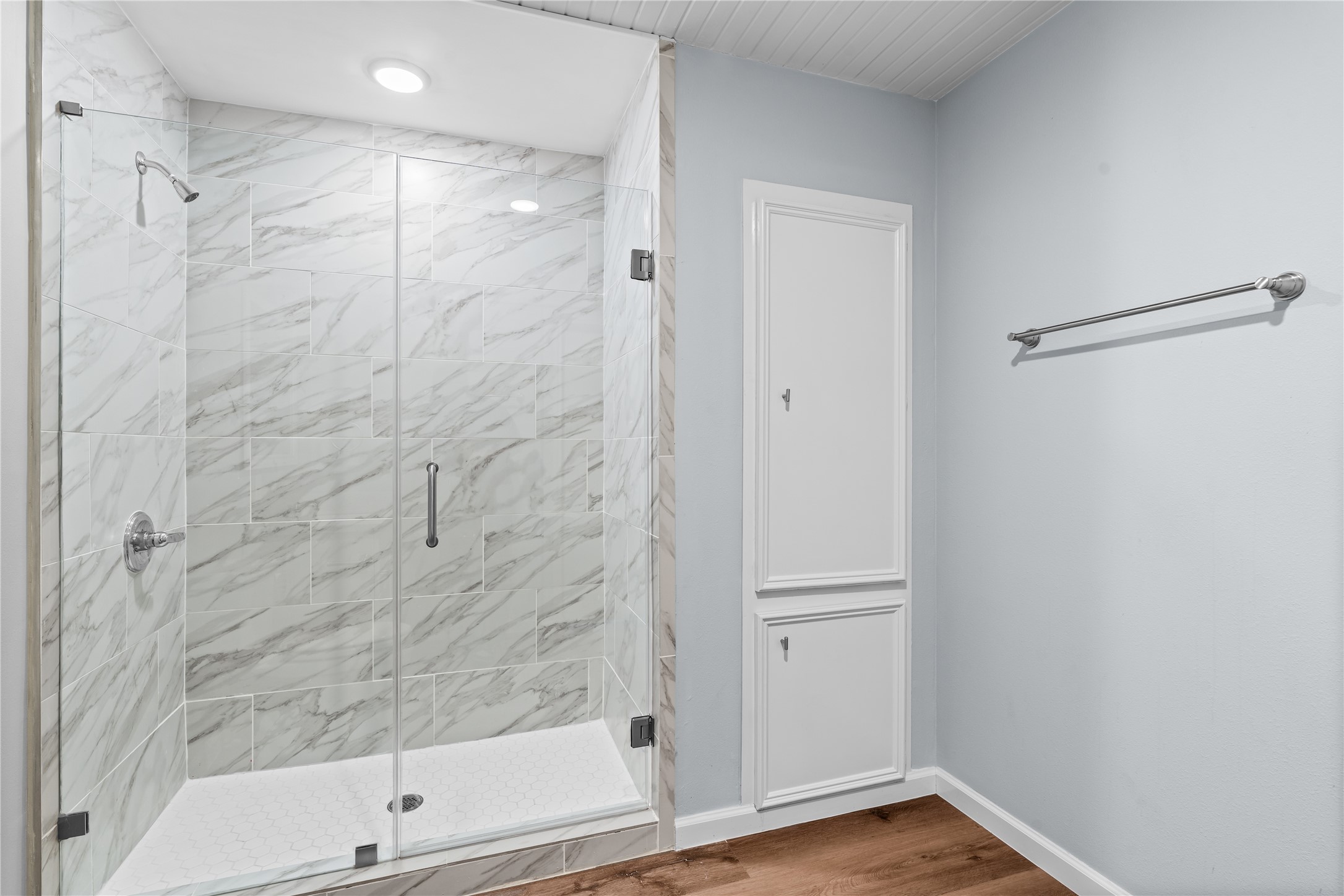 A generous walk-in shower with a frameless glass enclosure is complemented by built-in linen storage, adding convenience without sacrificing space.