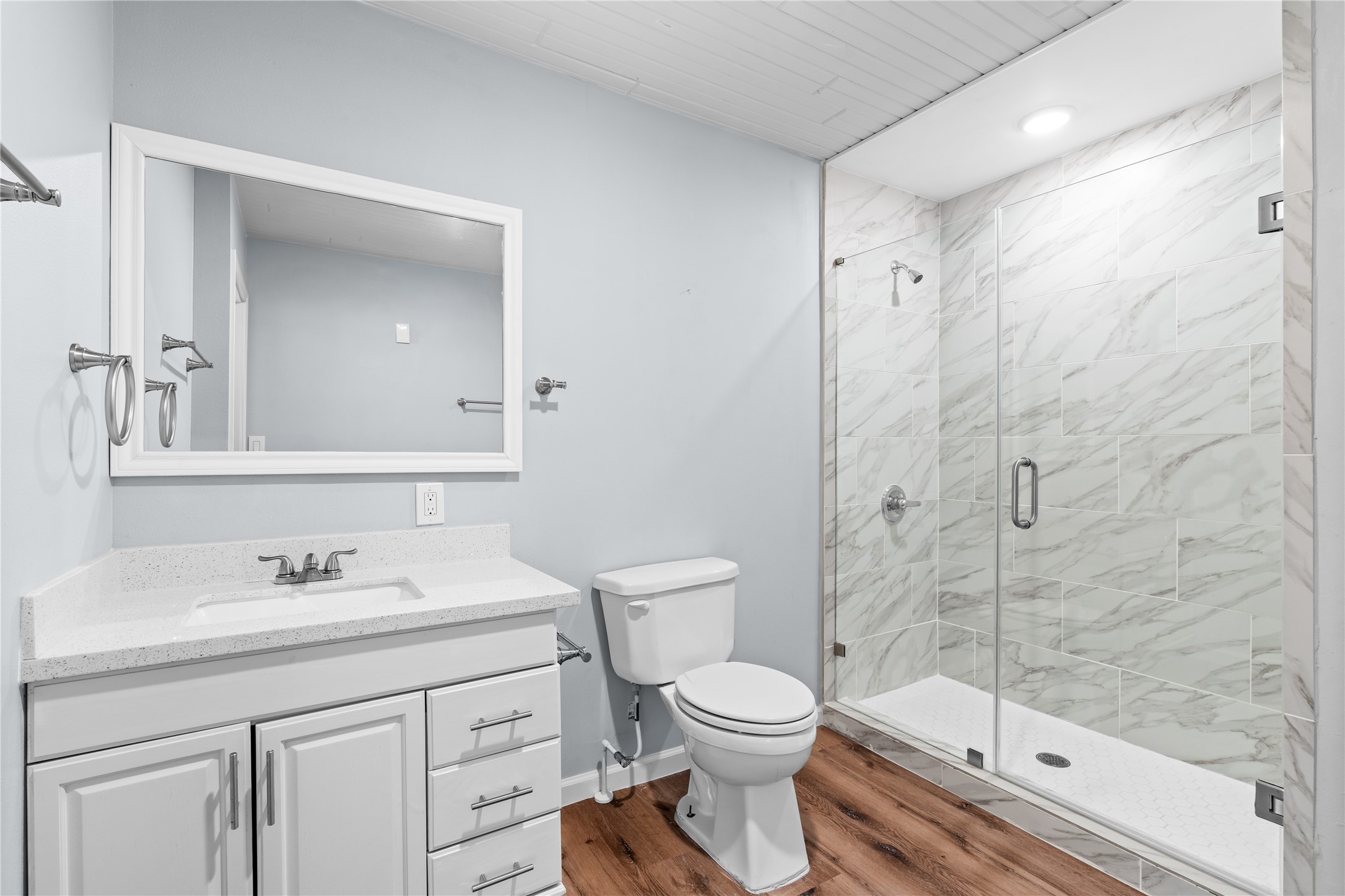 A generous walk-in shower with a frameless glass enclosure is complemented by built-in linen storage, adding convenience without sacrificing space.