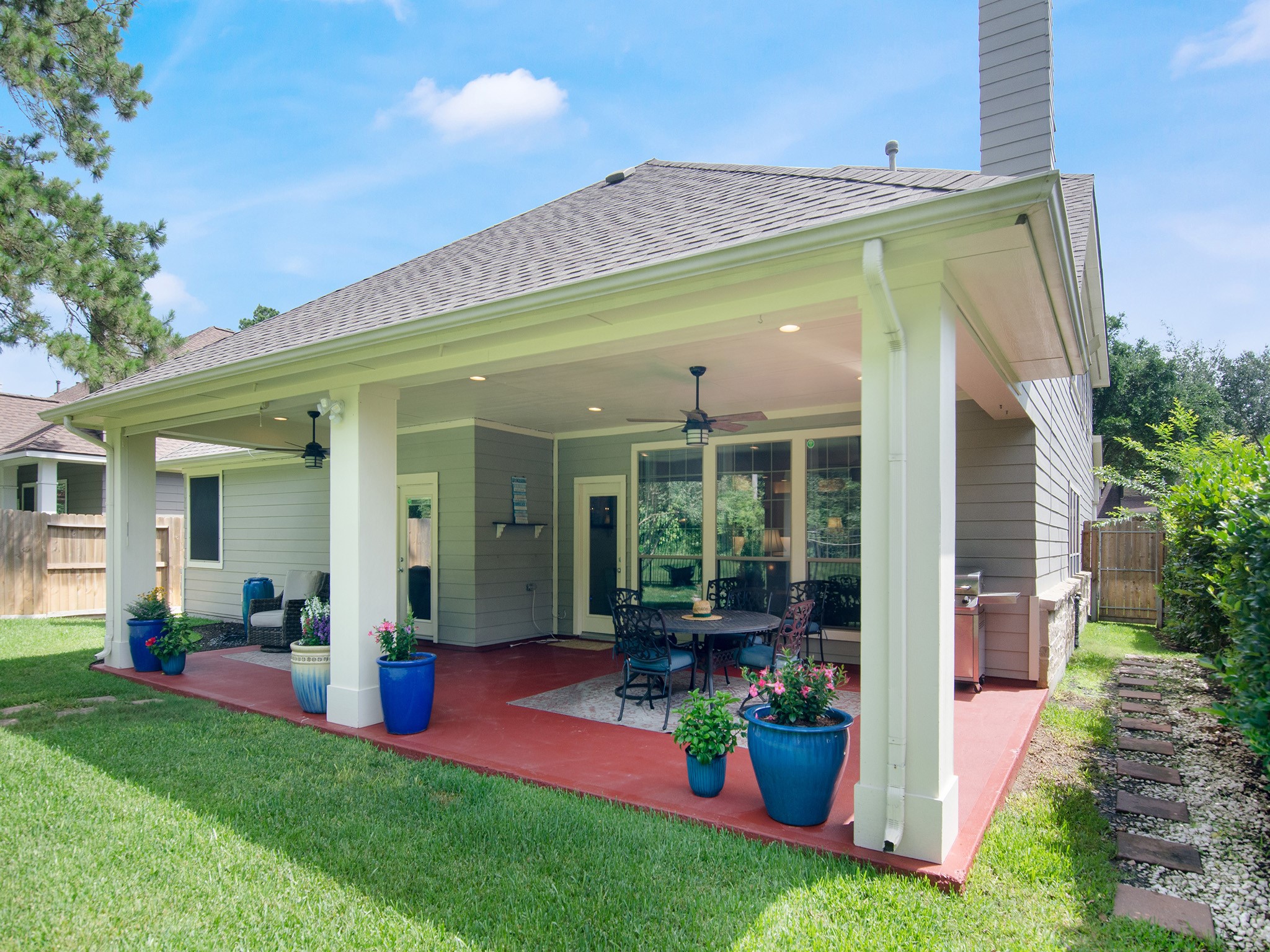 Expansive covered patio offers plenty of space for outdoor dining, grilling and relaxing, complete with recessed lighting, ceiling fans and an attractive wrought-iron fence.