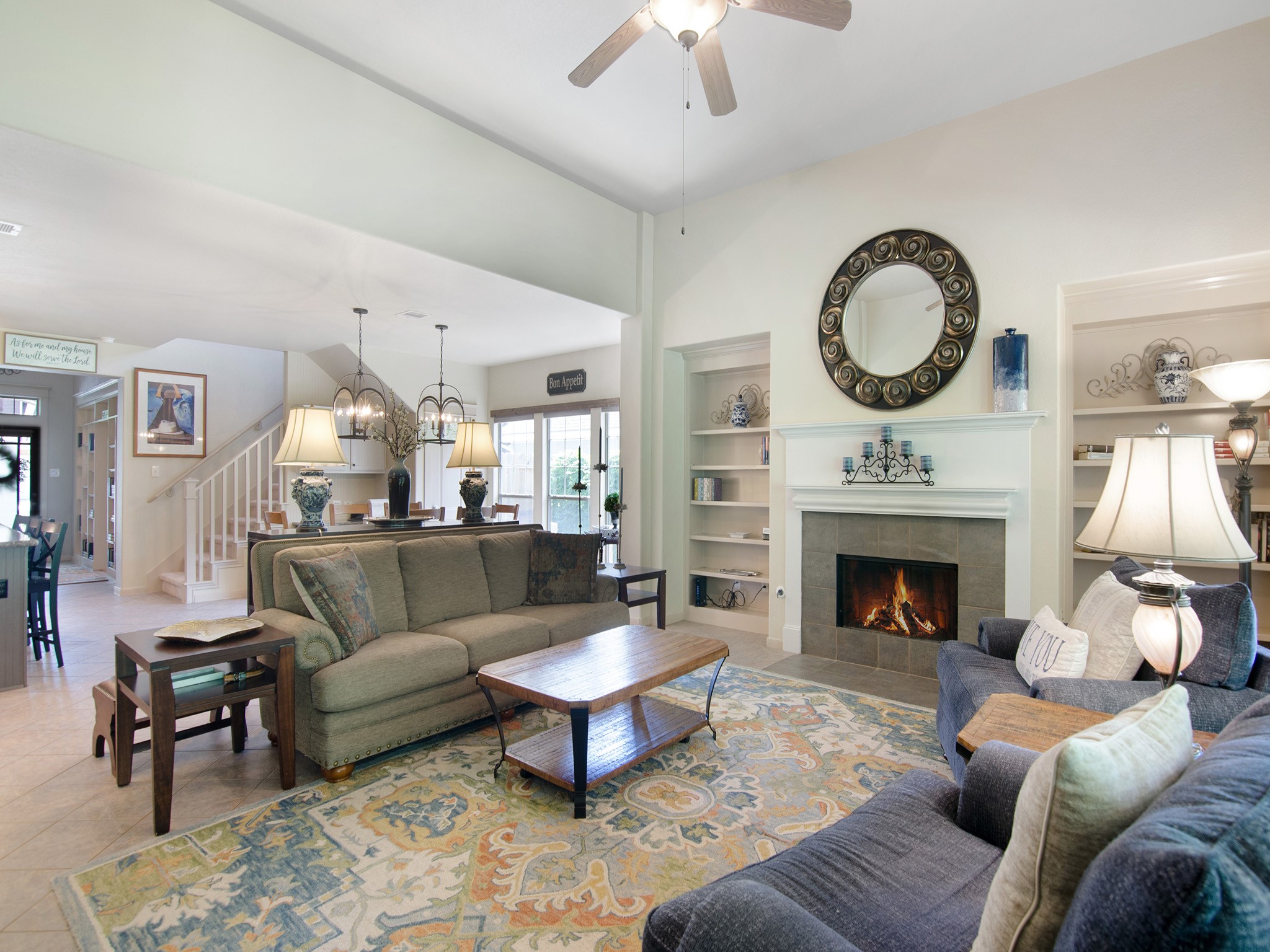 Cozy up by the inviting gas-log fireplace featuring a tile surround, crisp white mantel and symmetrical built-in shelving. Perfect for Texas winter weather.