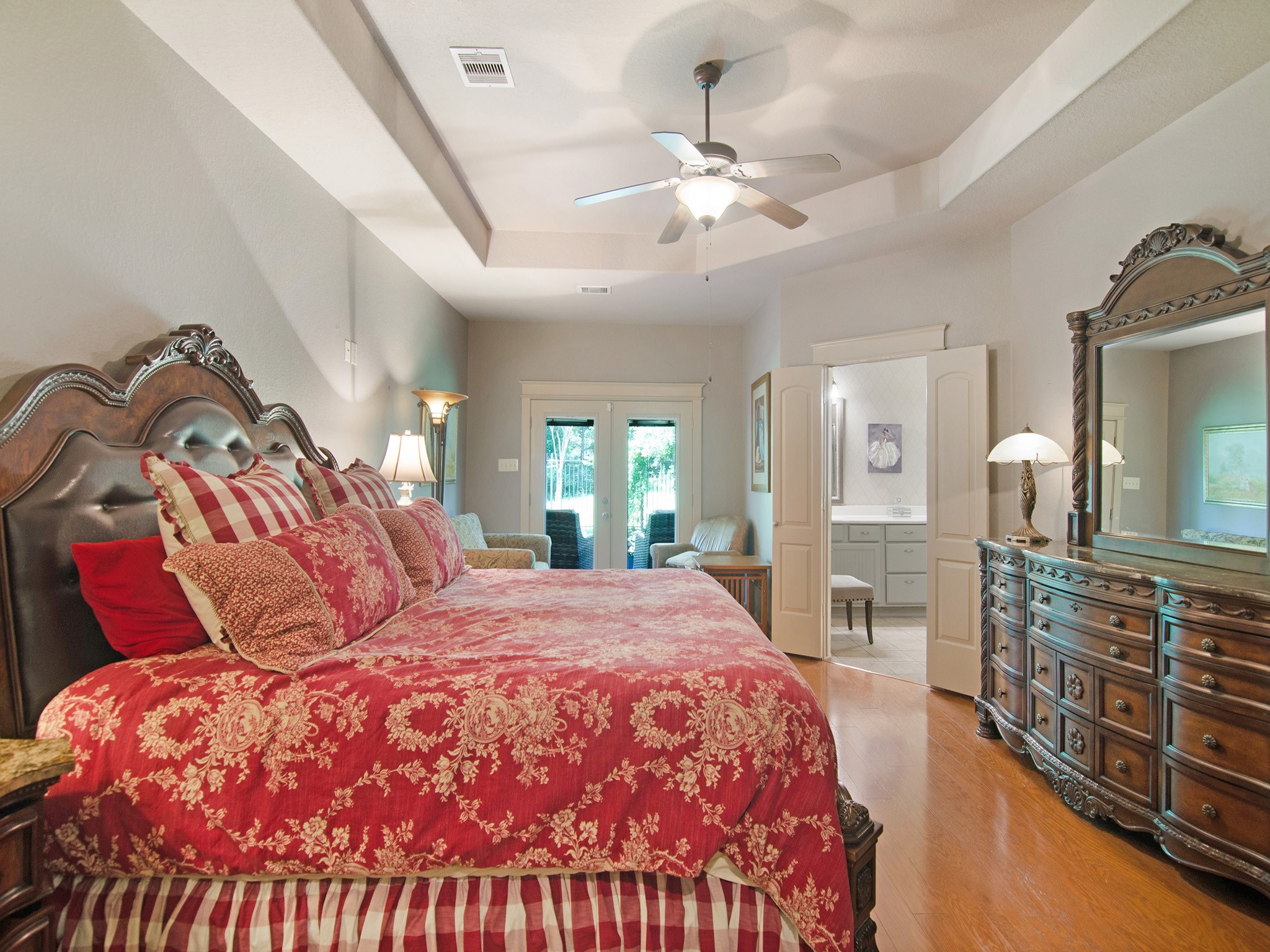 A generous sitting area creates the perfect space to relax with a book or morning coffee, while the French doors provide direct access to the peaceful backyard and covered patio.