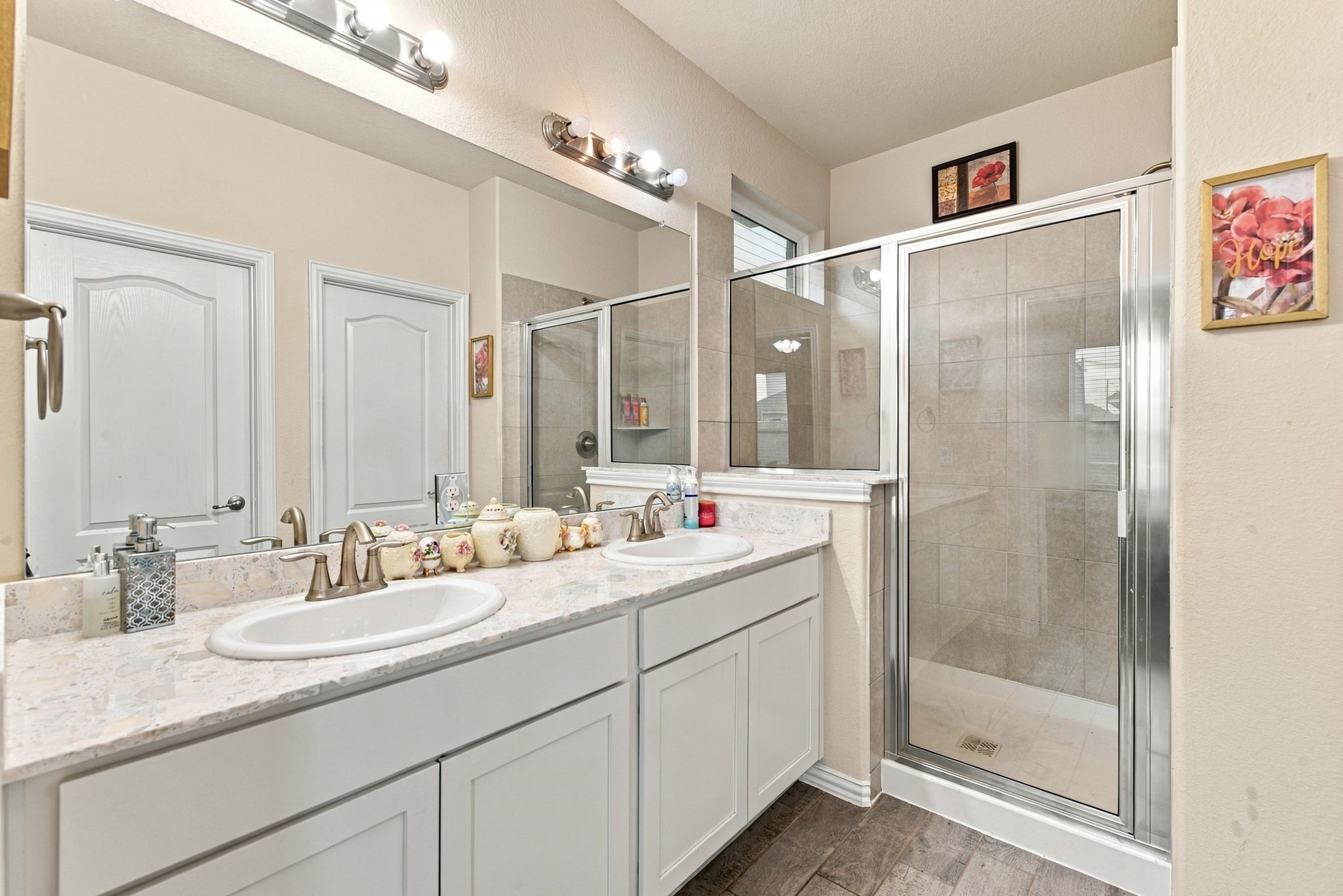 Ensuite bathroom featuring a dual-sink vanity with modern fixtures, complemented by a spacious glass-enclosed shower and tasteful tile accents.