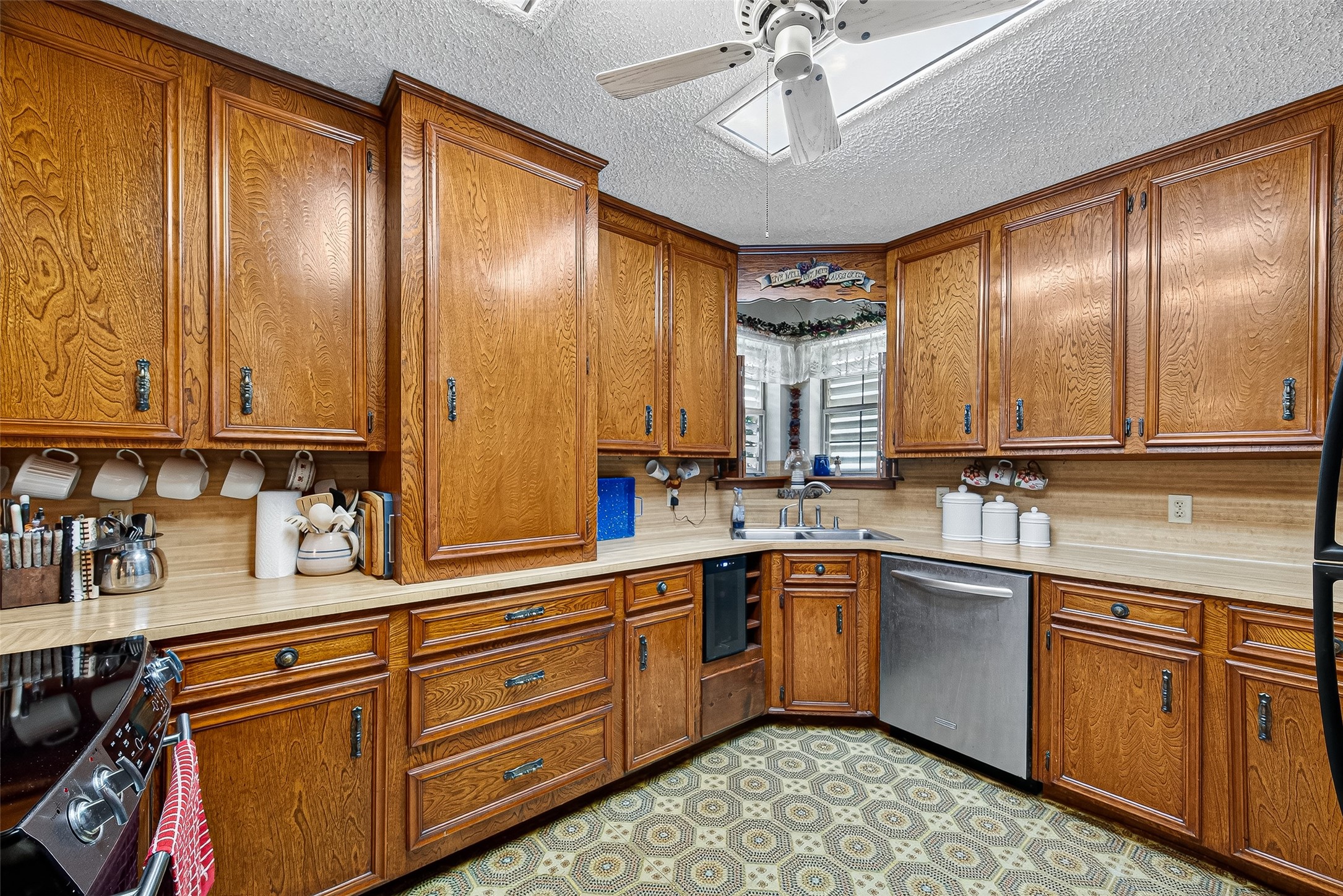 This kitchen features classic wooden cabinetry with ample storage, a stainless steel dishwasher, and a cozy corner sink. It has custom made cabinets and a rare large pantry cabinet in the interior of the kitchen making cooking an easy effort.