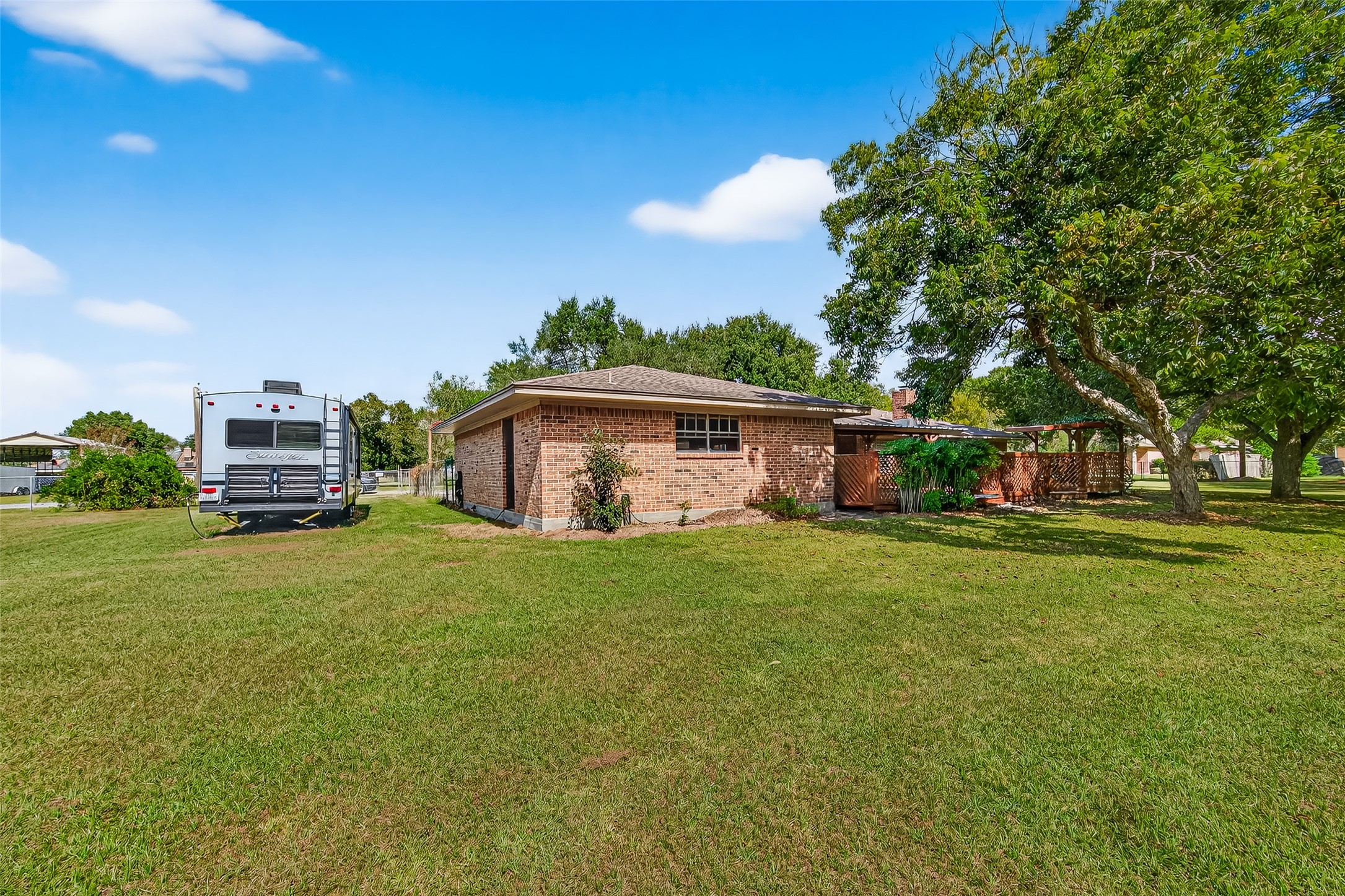 This photo shows a single-story brick house with a spacious backyard. There's a large grassy area and the property has a cozy, private feel with a covered patio area. Ideal for outdoor enthusiasts seeking ample space.