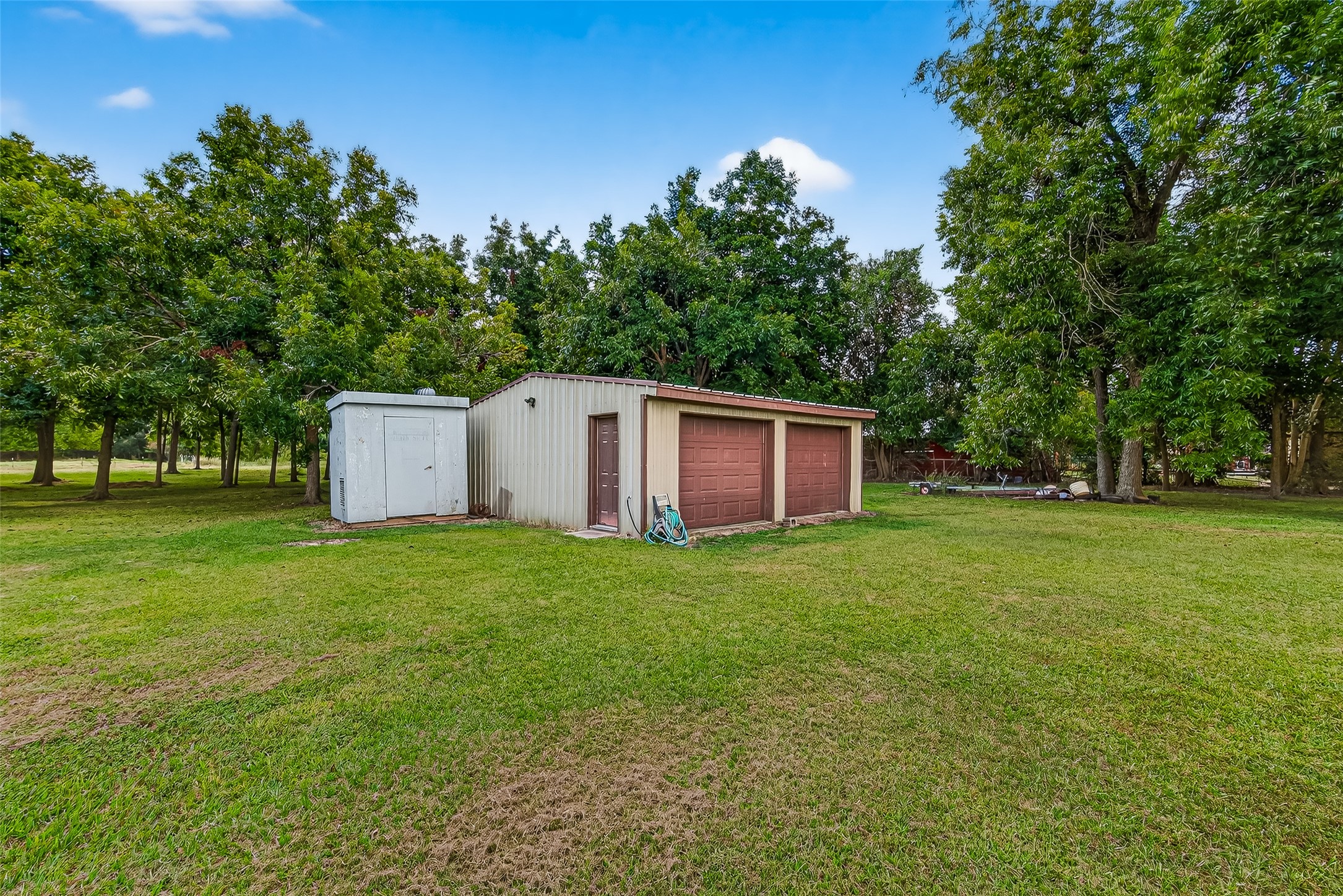 This photo shows a spacious backyard with a 24 x 24 workshop. The area is surrounded by offering a peaceful and private setting.