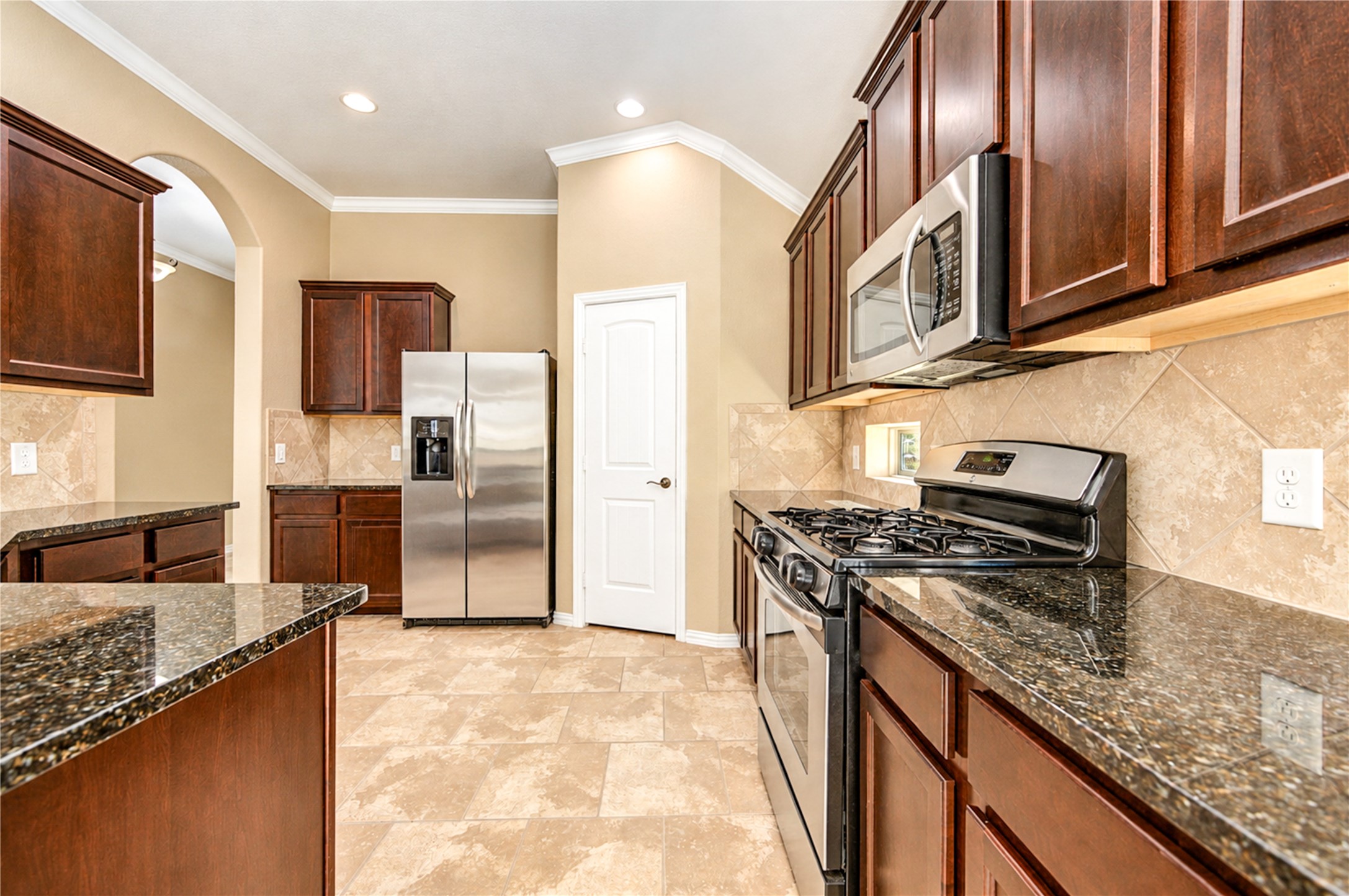 Stainless appliances, granite counters and a gas range sit within generous cabinetry in the kitchen.